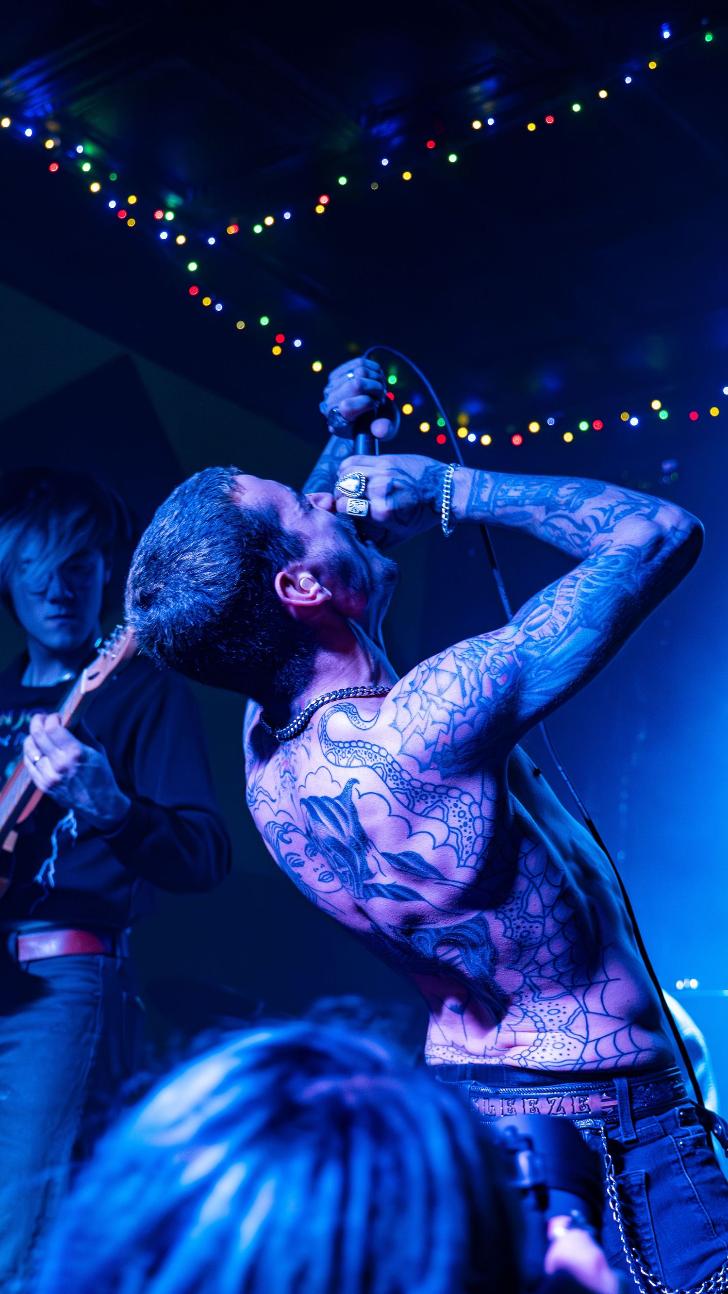 Performance scene under blue lighting with string lights creating festive atmosphere.