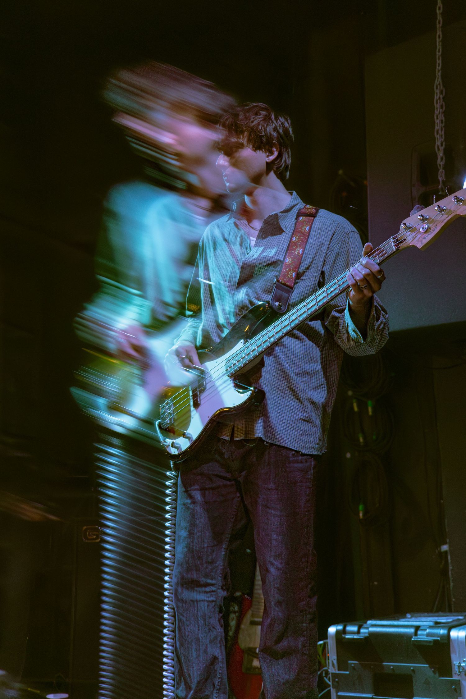 Guitar player performs on stage with motion blur and blue lighting effects creating a dynamic performance atmosphere.