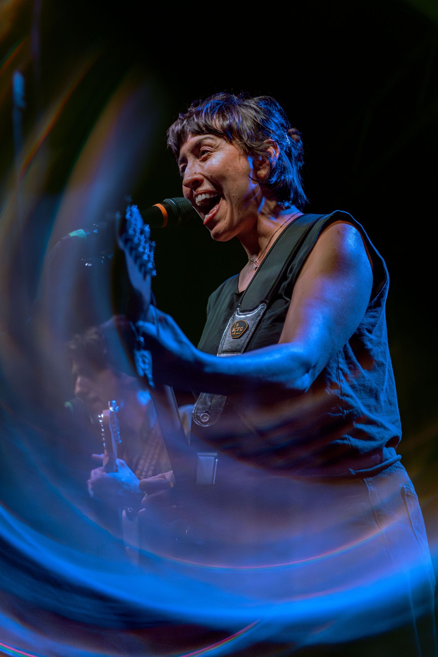 Concert performer on stage in blue lighting creating dynamic motion blur effect during live music show performance.