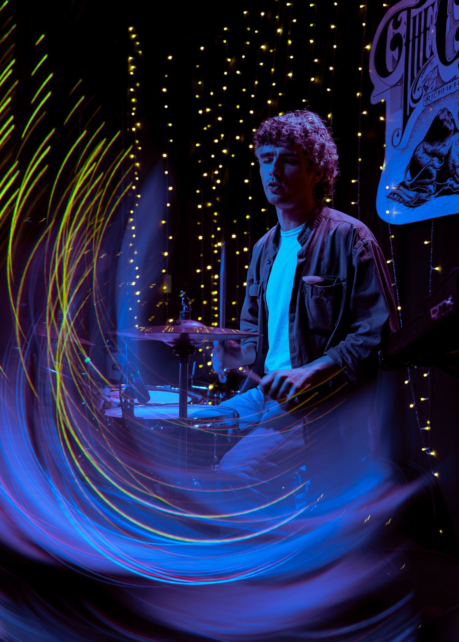 A sequence of long exposure photos creates blue light trails against a dark background with twinkling lights.