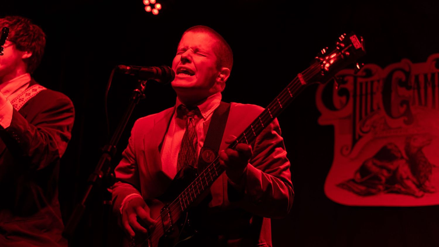 Musicians performing on stage bathed in dramatic red lighting during an intense concert moment.