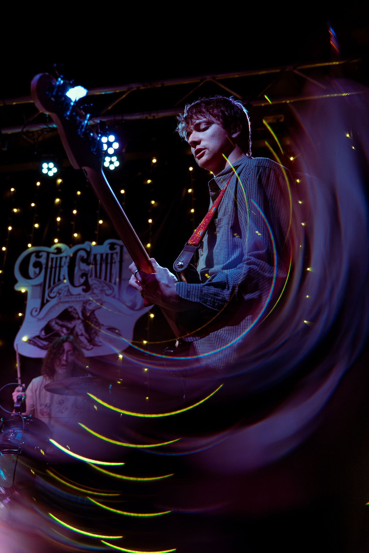 A musician performs on stage at the Chit Chat Lounge with atmospheric purple lighting and glowing decorations.