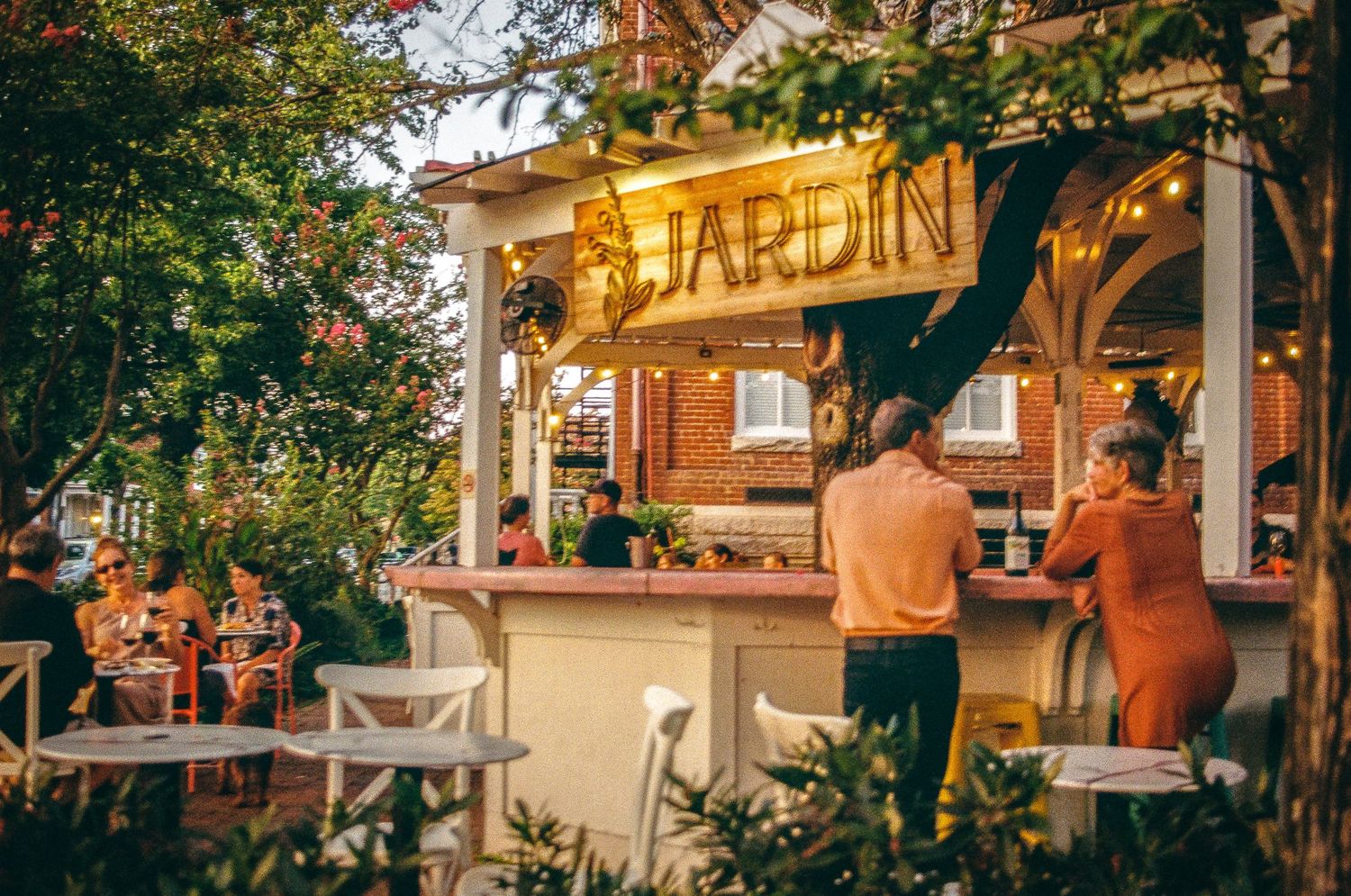 Rustic outdoor bar named Jardin with warm lighting and garden atmosphere.