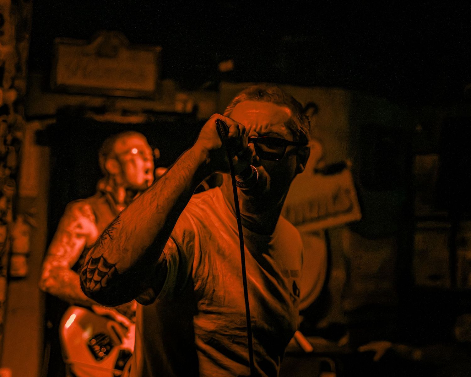 Concert audience member silhouetted in orange lighting at a music venue.