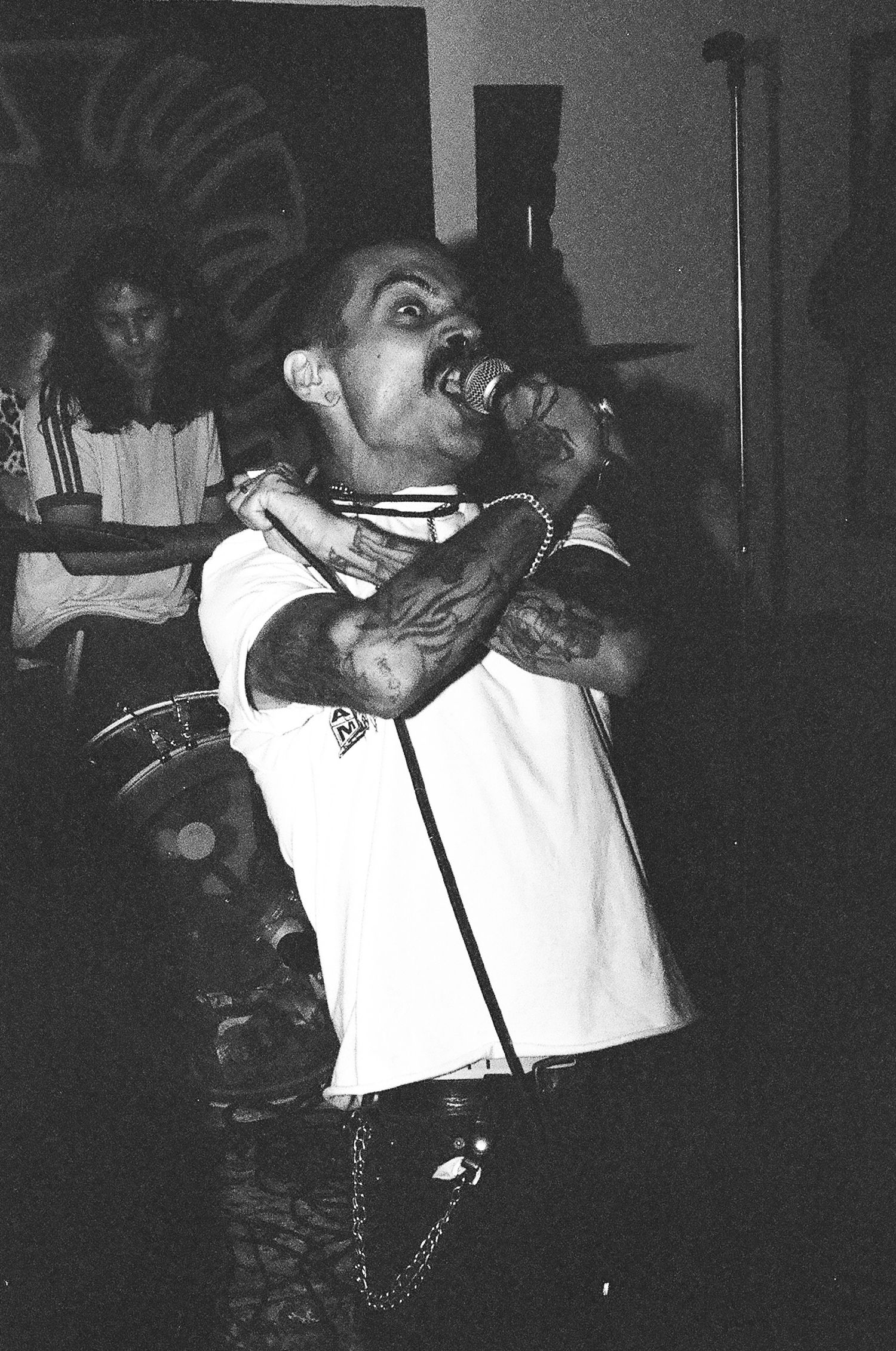 Black and white photo showing energetic punk rock performance in small venue.
