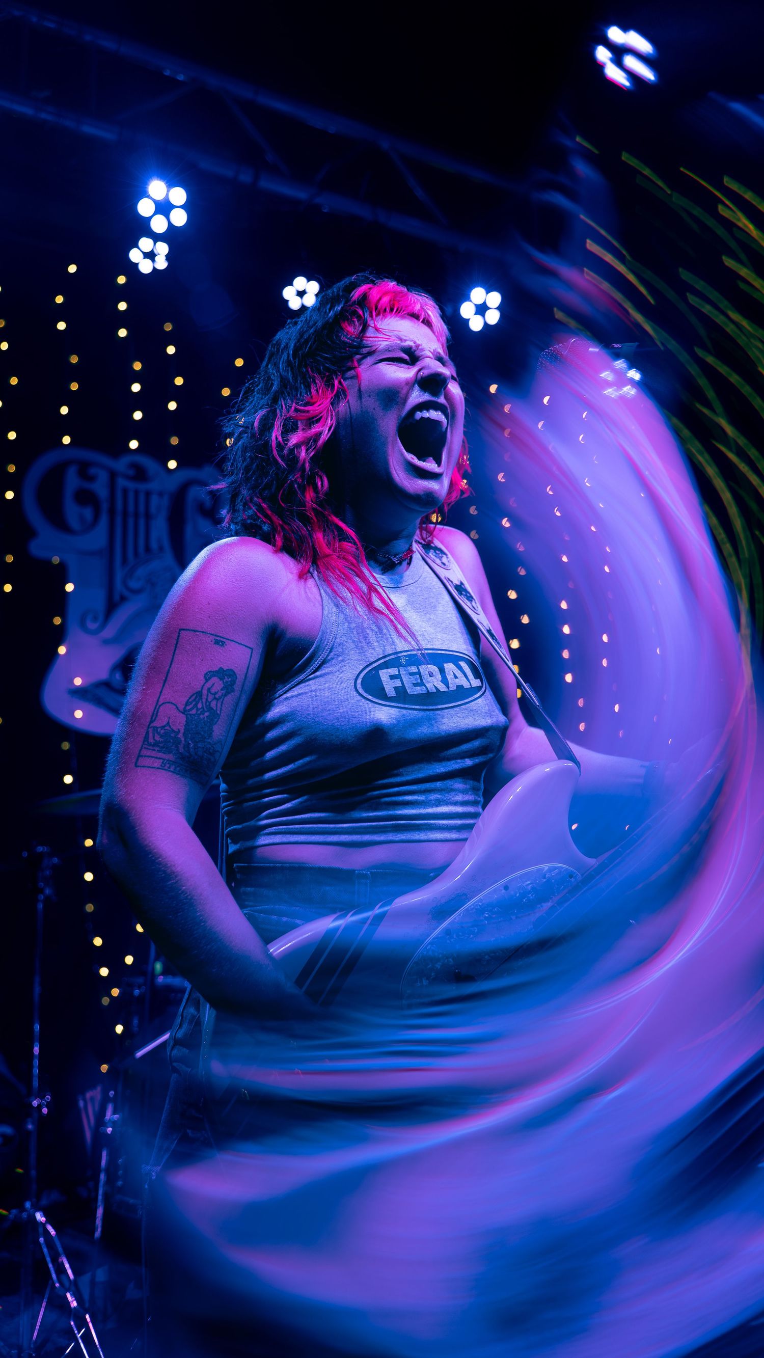 Performance on stage with blue and pink lighting creates swirling motion blur effect in nightclub setting.