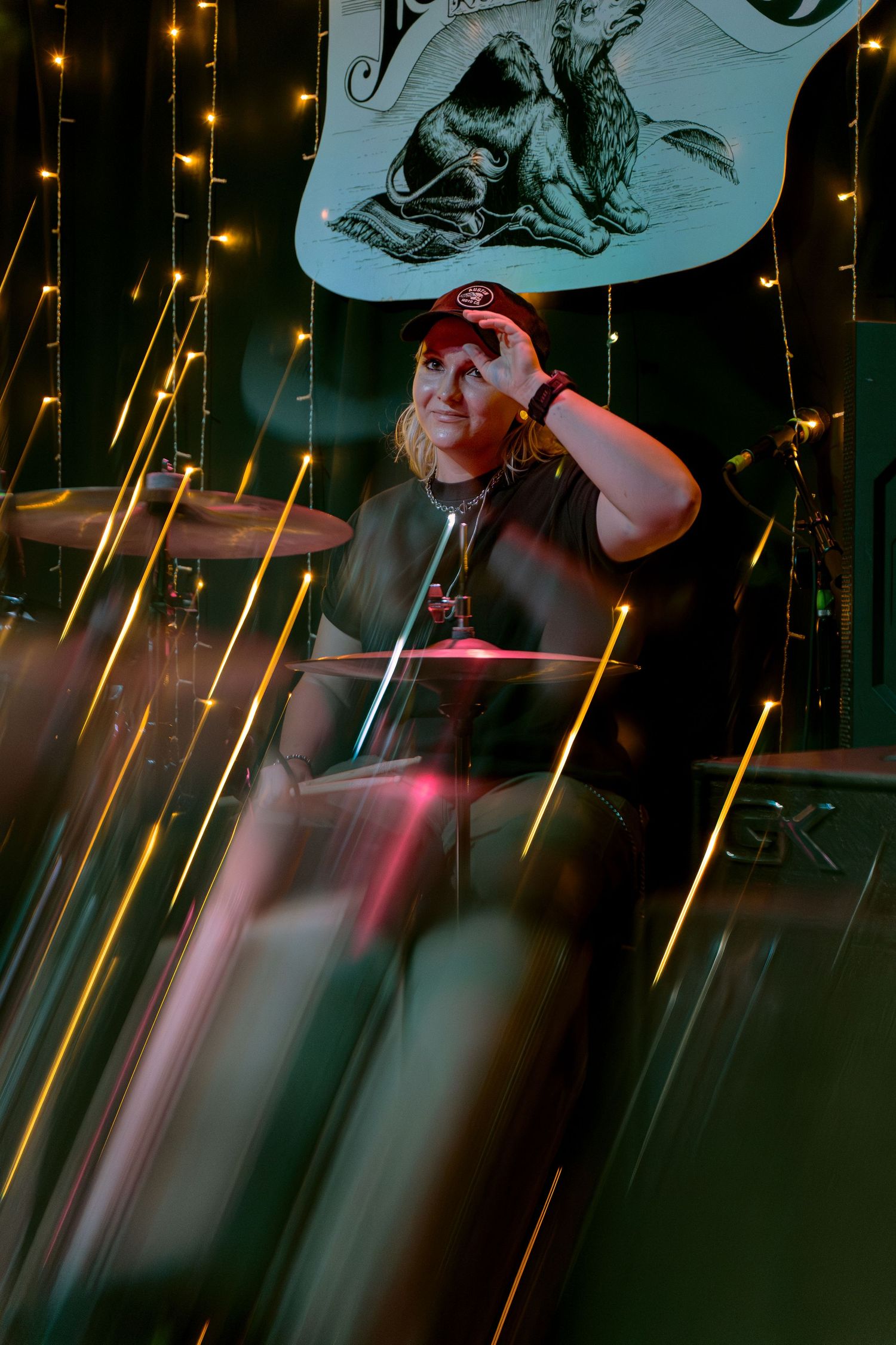 A series of motion blur photos showing a performer during a night concert with glowing string lights in the background.