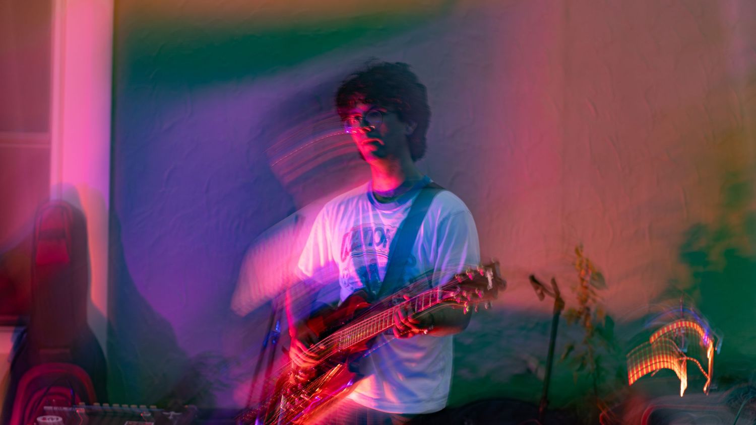 Guitarist performing on stage illuminated by vibrant pink and purple lighting effects.