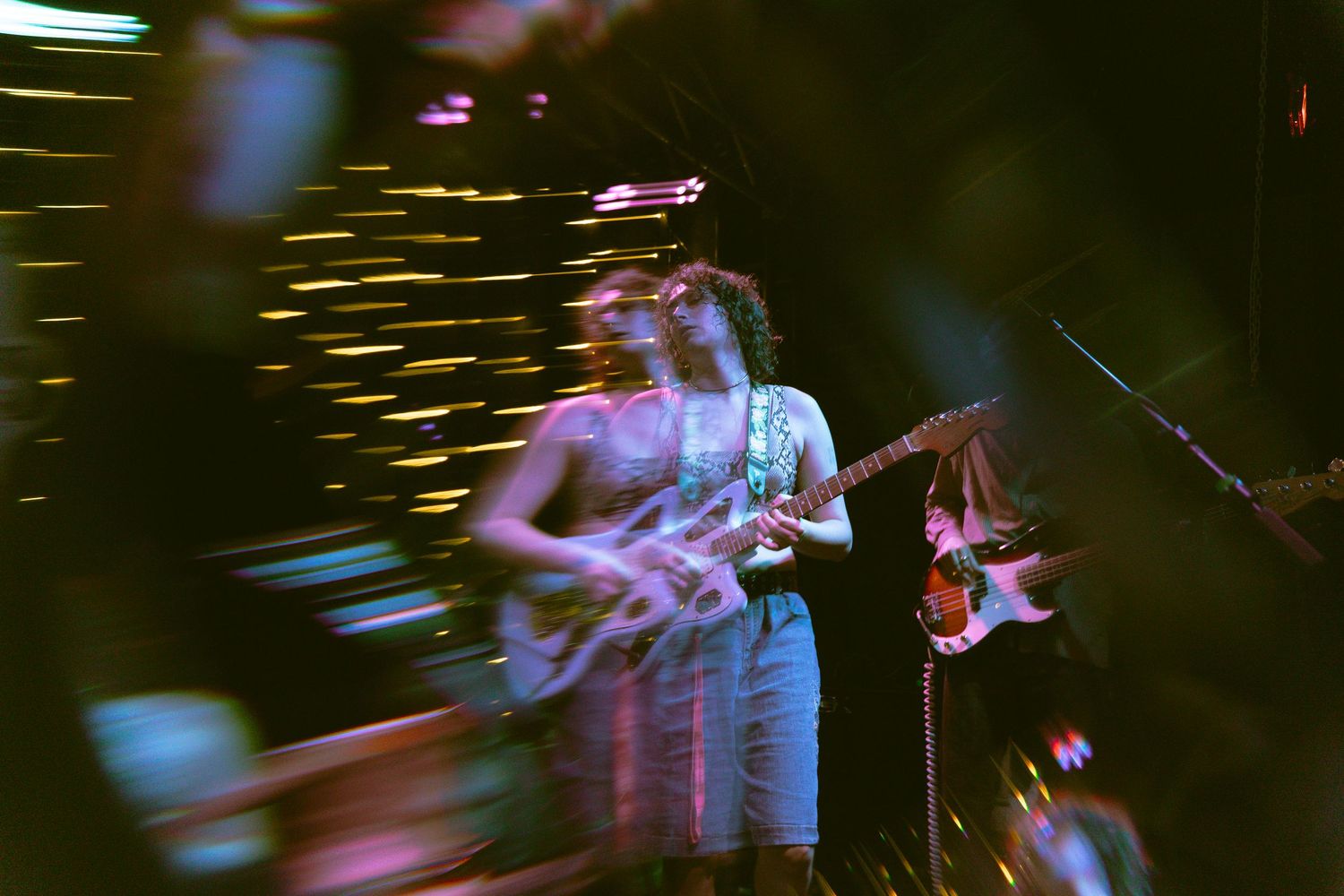 Concert photographers capture a performer on stage through a hazy purple lighting effect at a live music show.