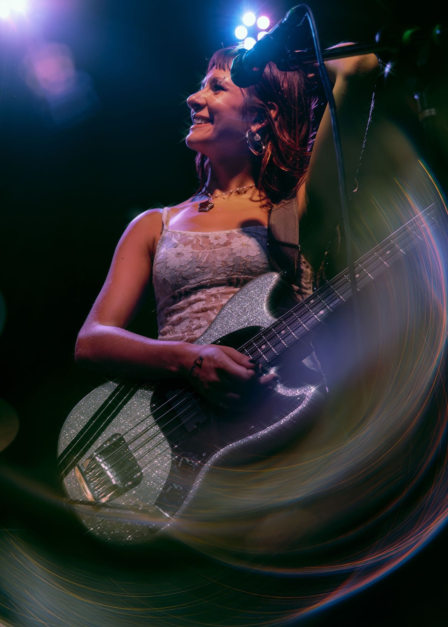A musician plays bass guitar in a dynamic performance captured with creative fisheye lens distortion against dark stage lighting.