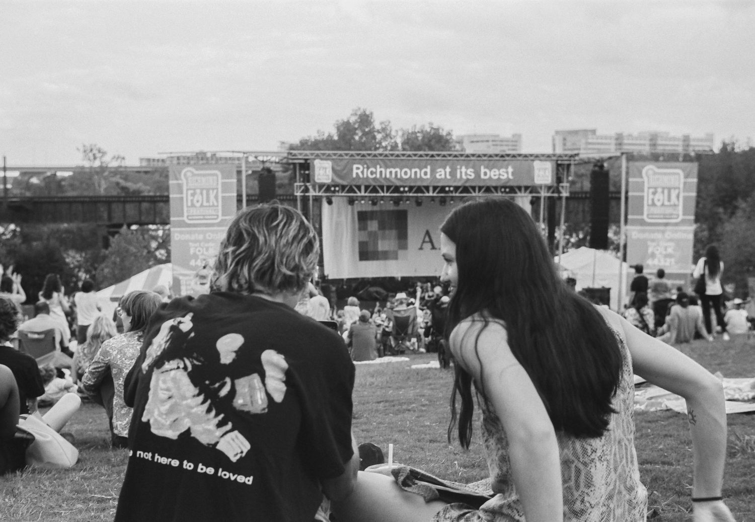 Monochrome panorama of festival crowd outdoors during daytime event.