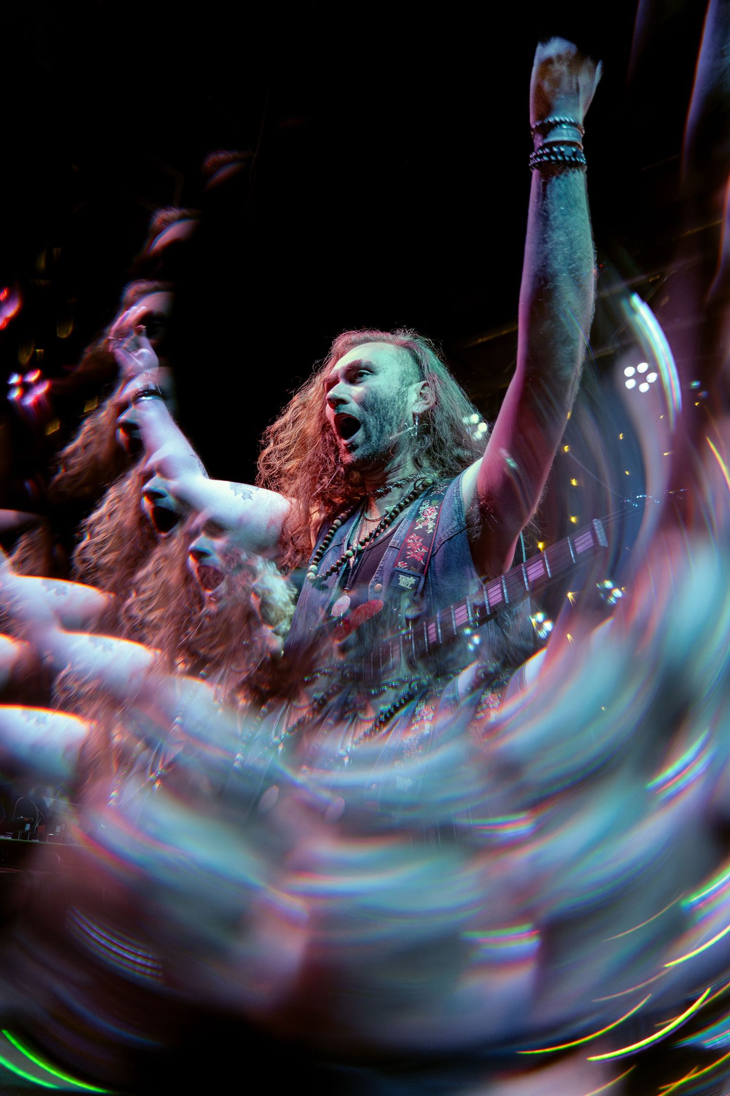 Abstract motion blur photograph showing spinning lights and movement in dark concert environment creating swirling patterns.