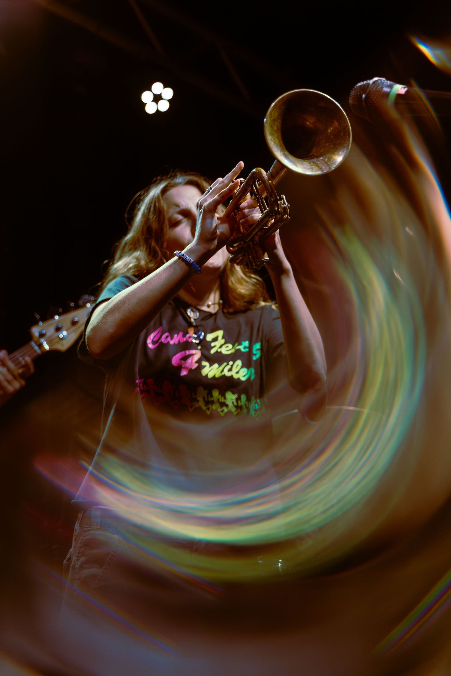 A motion-blurred performance sequence shows swirling lights and movement creating abstract colorful patterns on stage.