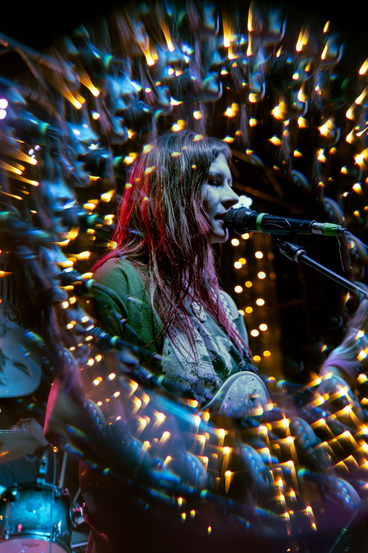 Musician performs on stage with twinkling golden and blue lights creating a dreamy bokeh effect in the background.