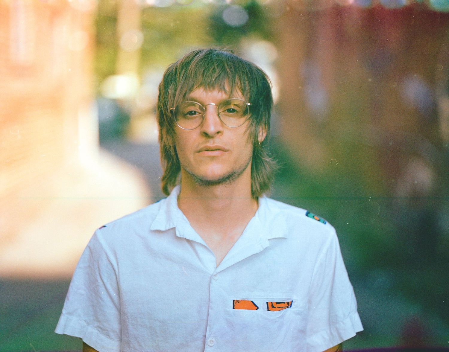 Person in white polo shirt photographed outdoors in warm evening light.