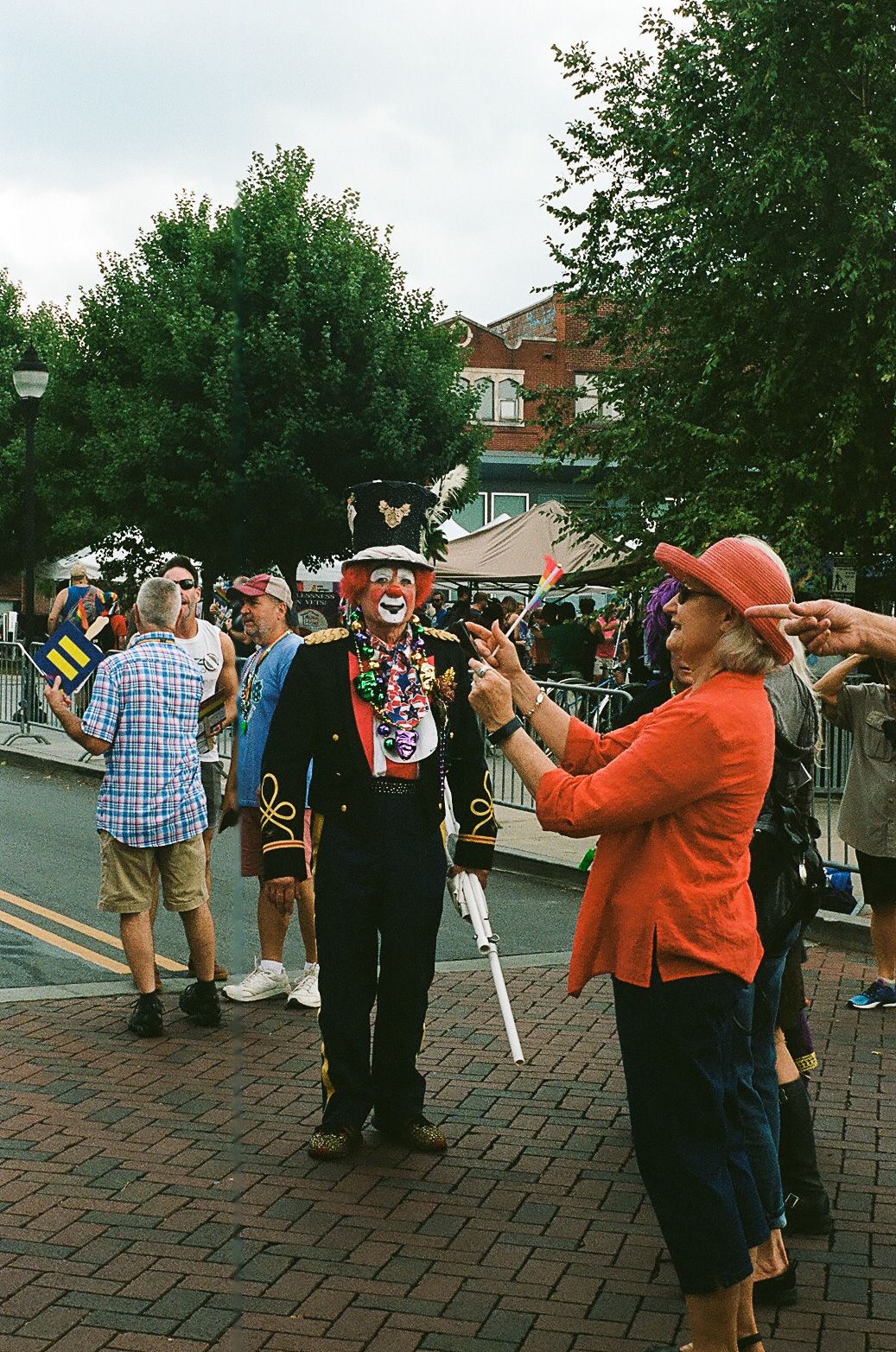 Festive street scene with costumed performers interacting with spectators at an outdoor event.