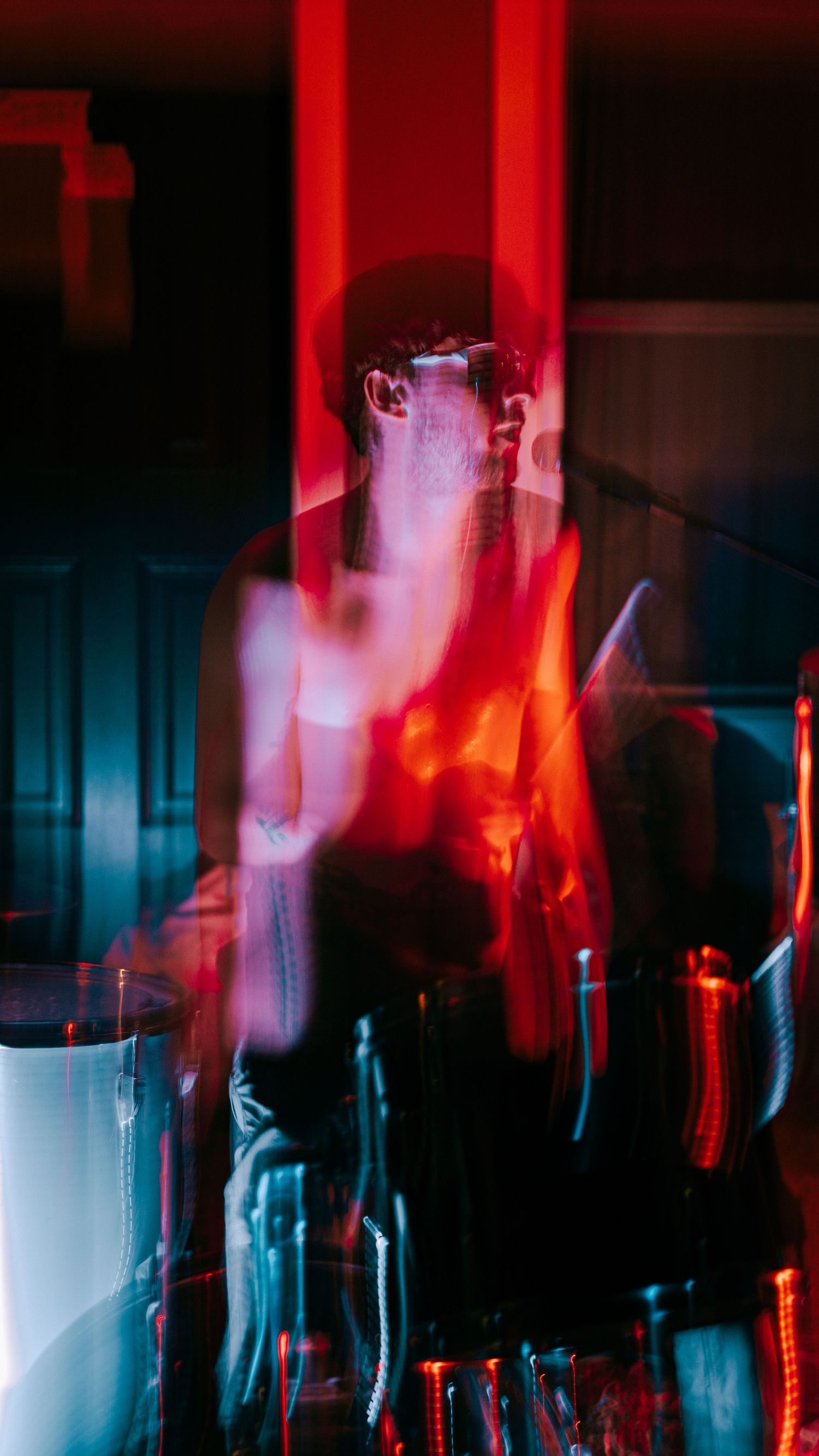 Abstract concert photography with red lighting and motion blur creating an ethereal performance atmosphere.