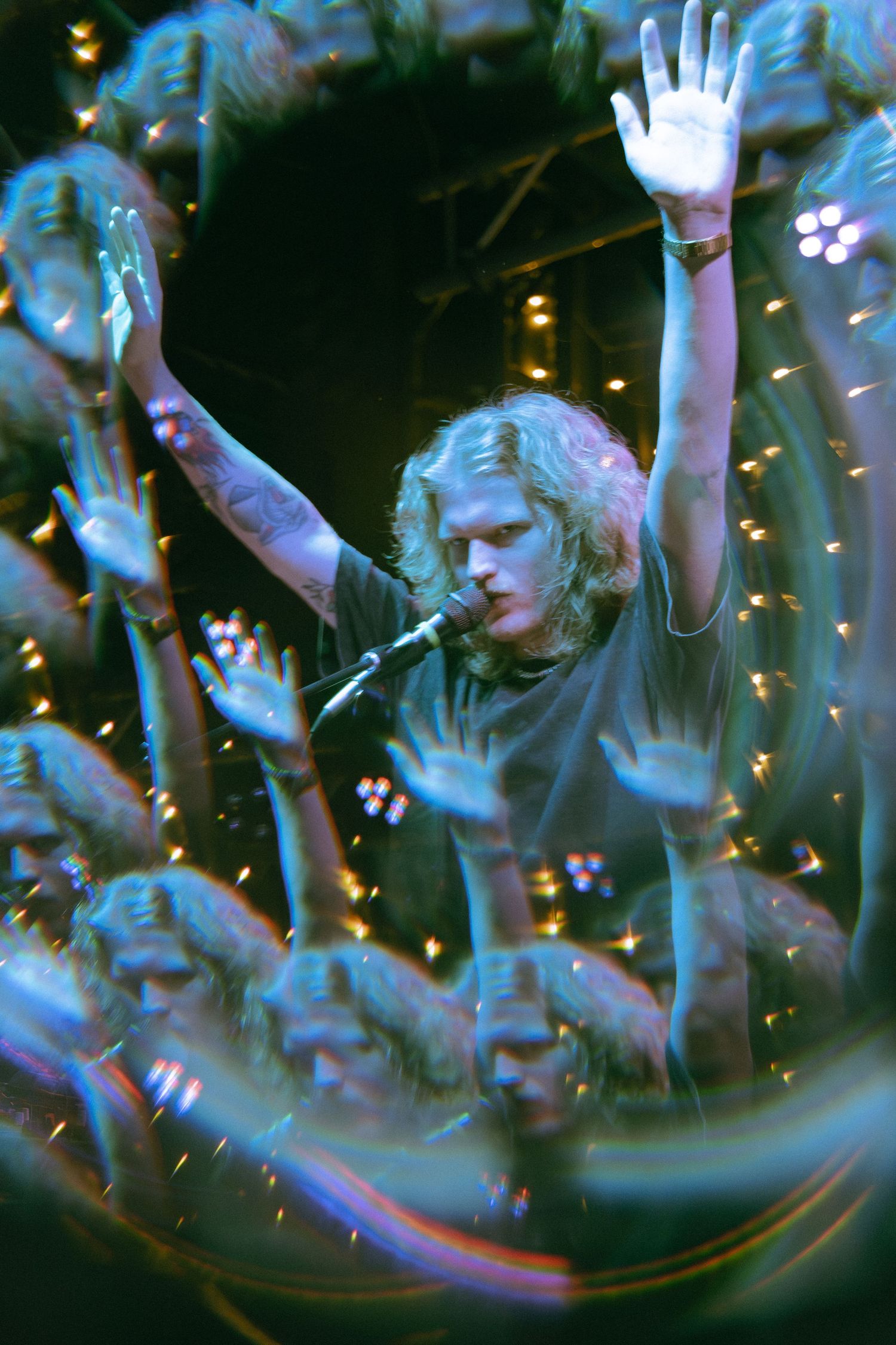 A sequence of three abstract, blurry photos showing silhouettes of raised hands against a dark background with twinkling lights.