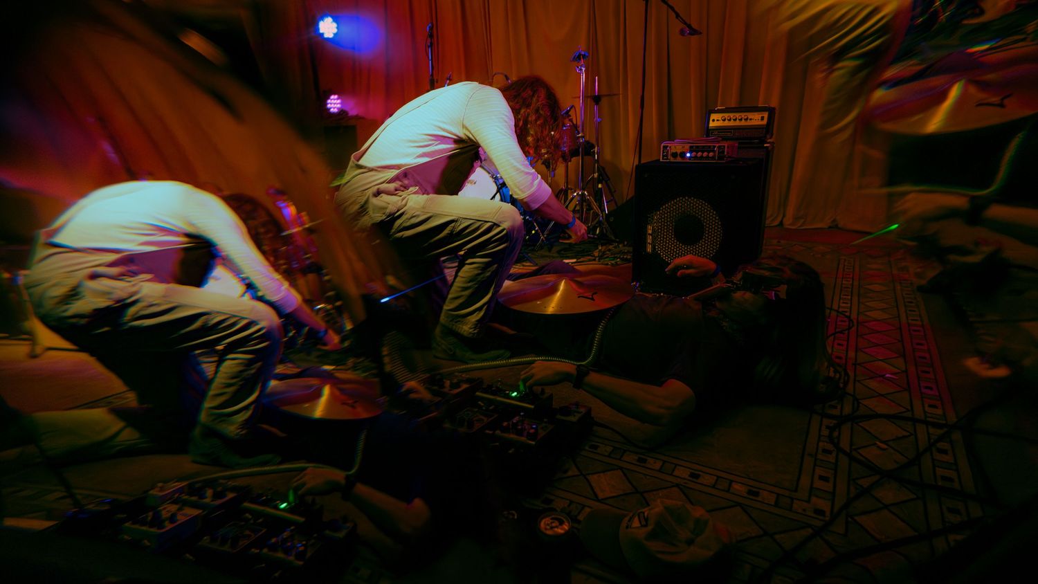 Time lapse sequence shows someone stretching out on wooden studio floor under blue lighting.