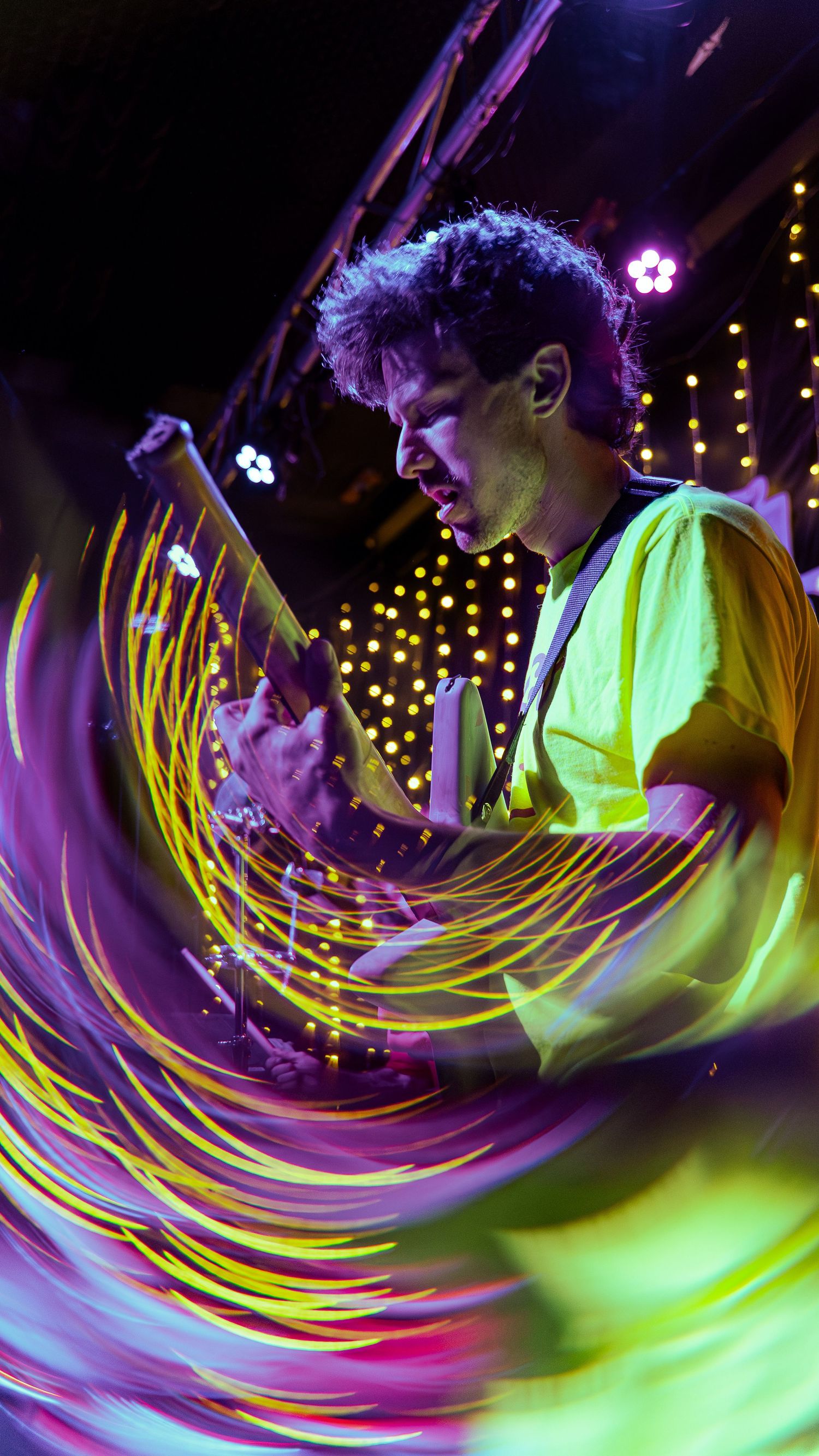 Colorful spiral light trail effect with neon yellow and purple streaks creates dynamic motion blur in nightclub atmosphere.