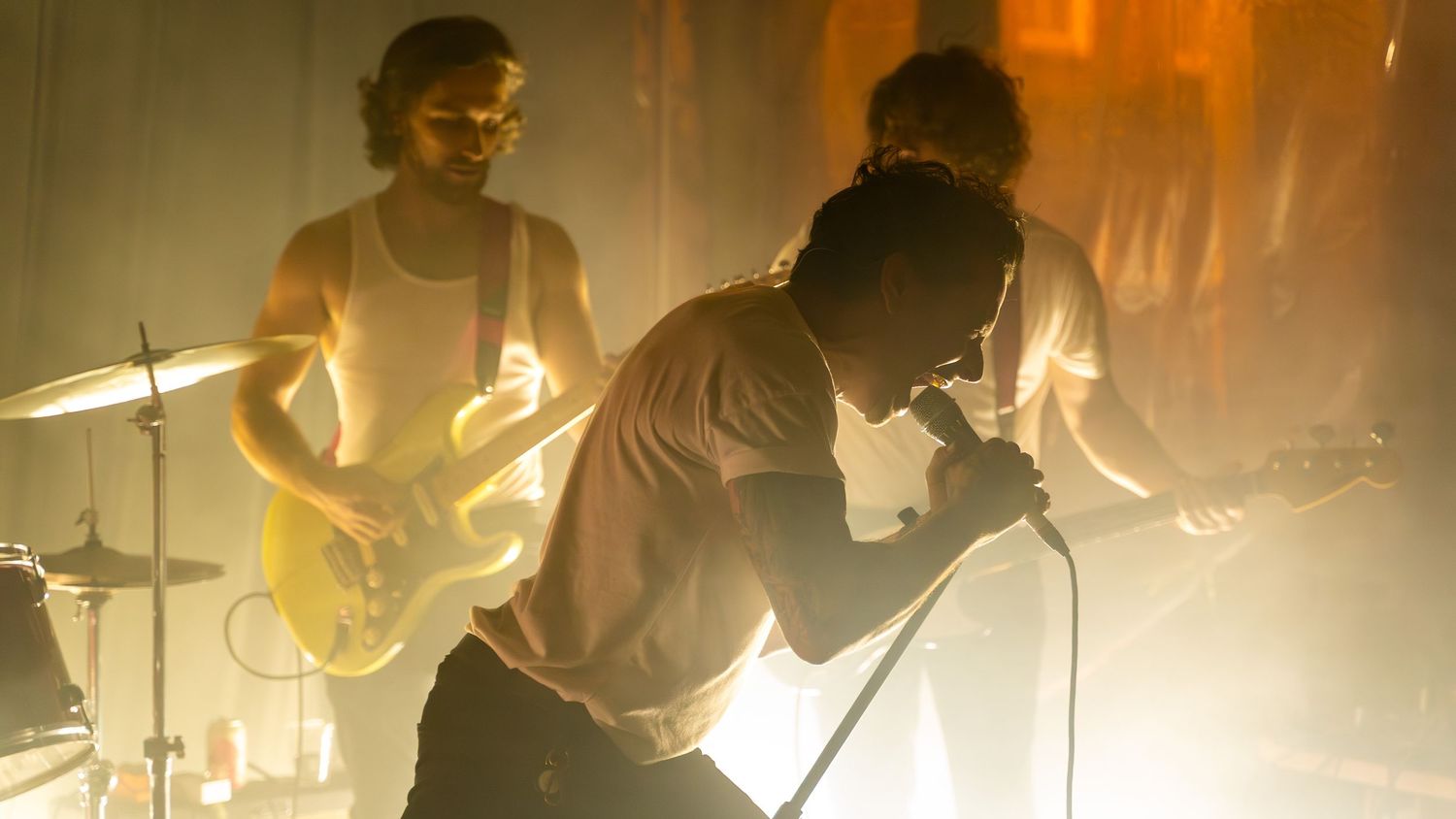 Silhouetted band performs on stage with dramatic backlit orange lighting effects.