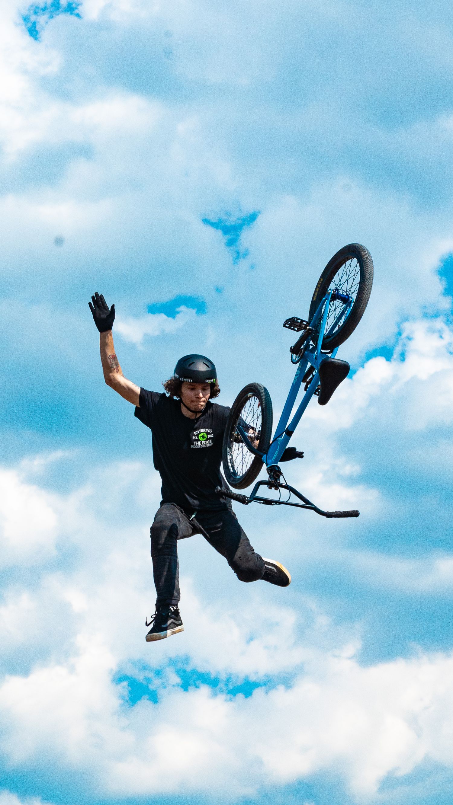 BMX rider launches into sky performing dramatic aerial maneuver with bike.
