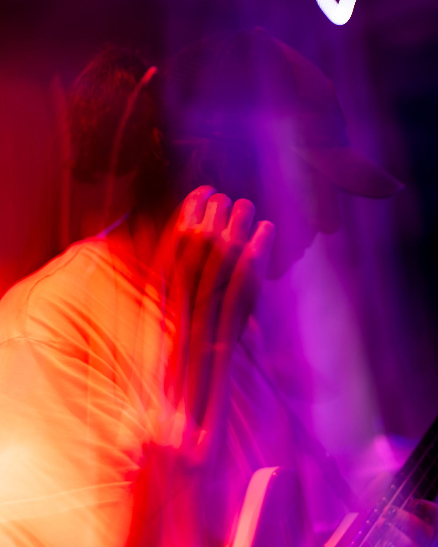 Abstract concert photography with red and purple lighting creating motion blur effect.