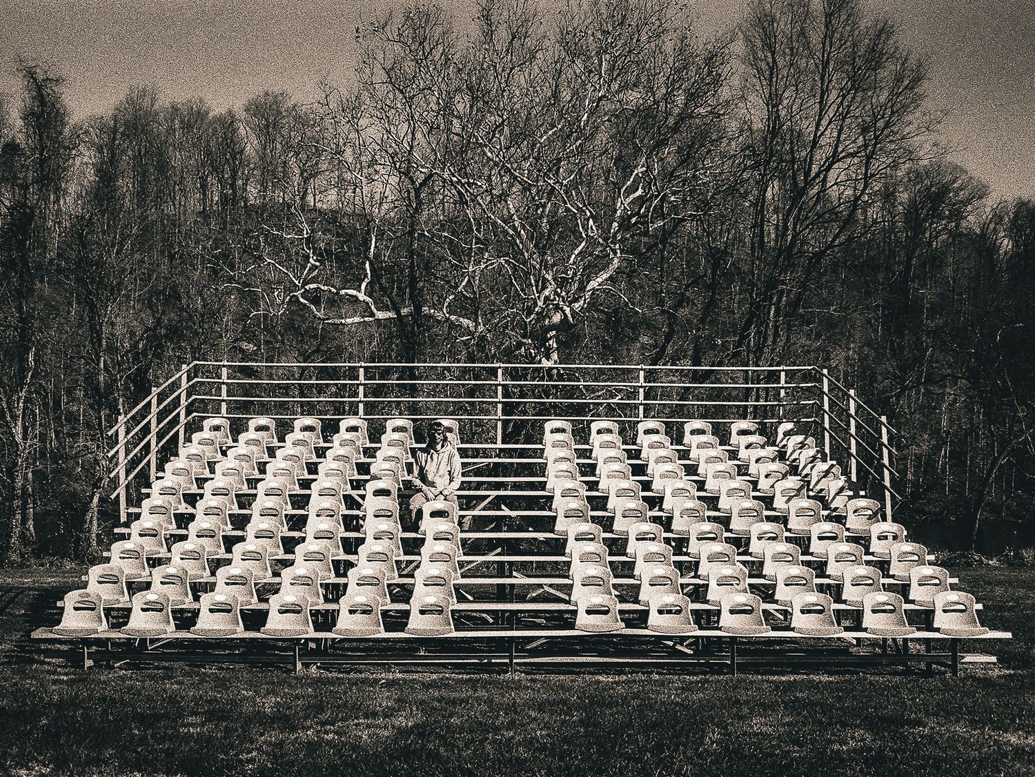 Vintage black and white photo of empty bleachers in an outdoor setting.