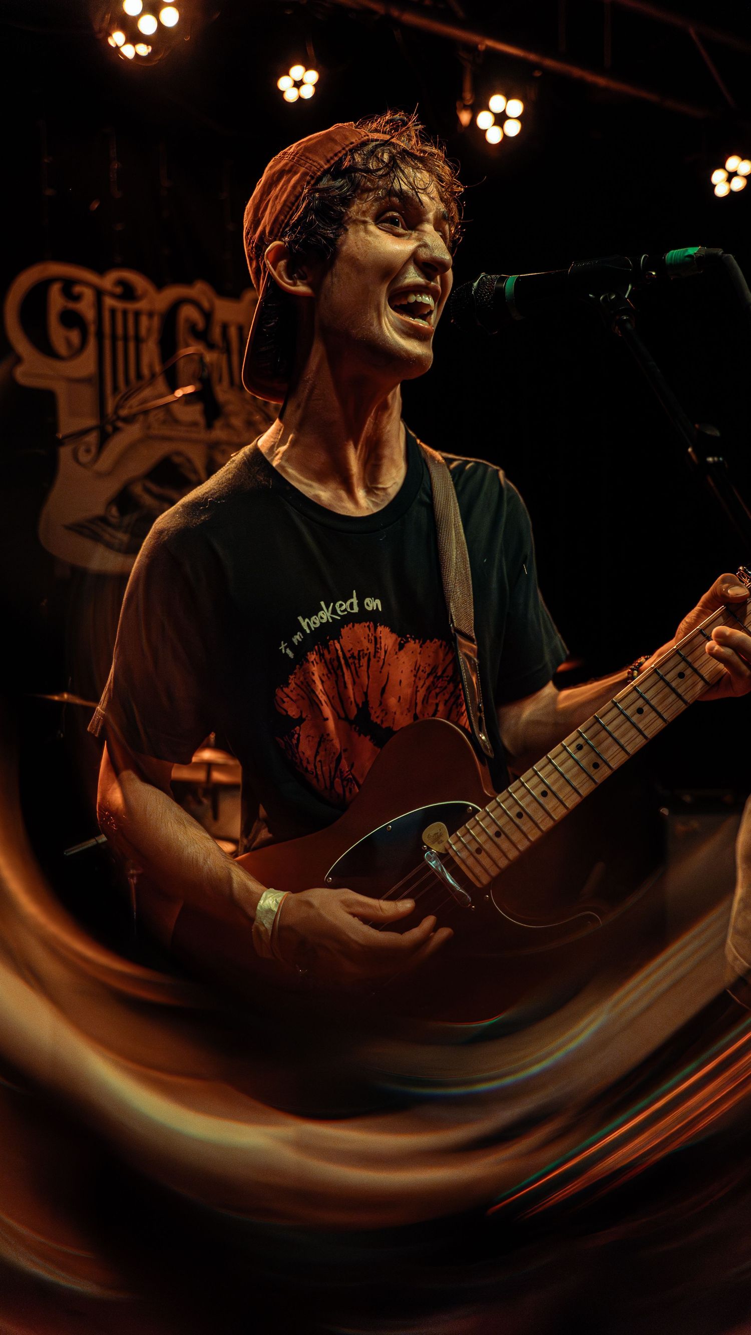 Musician performing on stage with guitar shown in a sequence of dramatic low-angle shots under warm stage lighting.