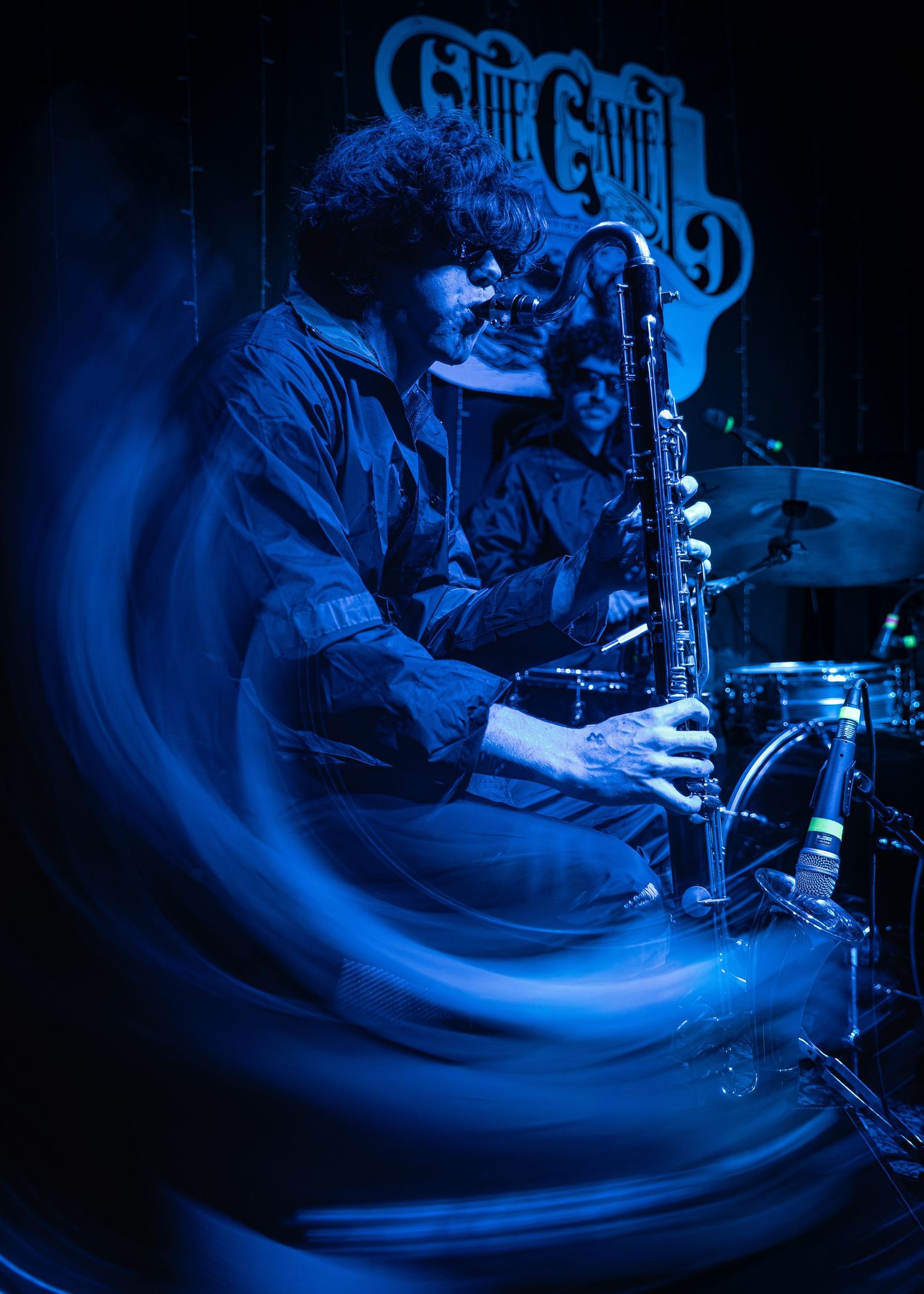 Multiple exposure photo shows musician playing a clarinet instrument in blue lighting during performance scene.