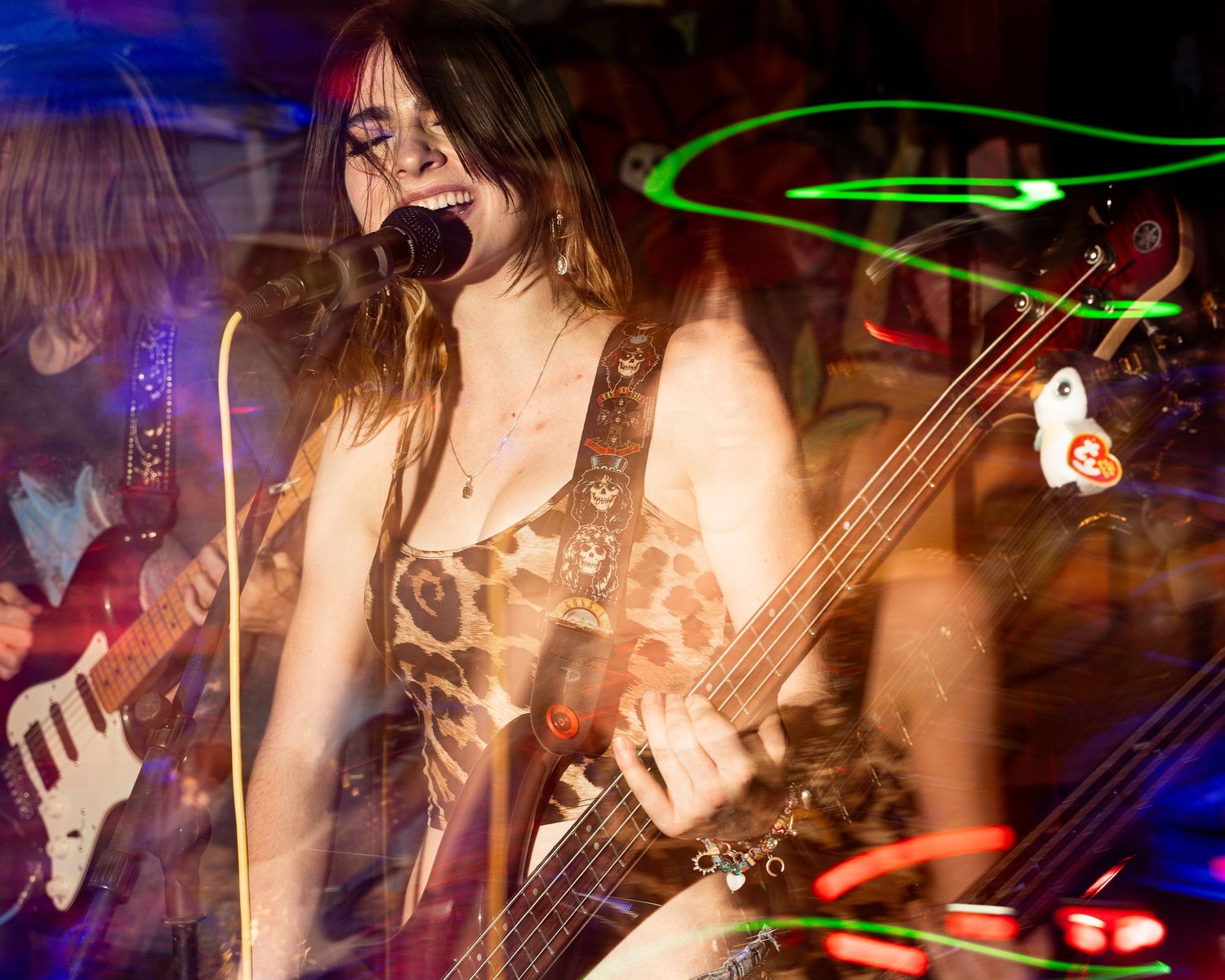 Musician playing bass and singing into microphone with dynamic blue and red lighting effects.