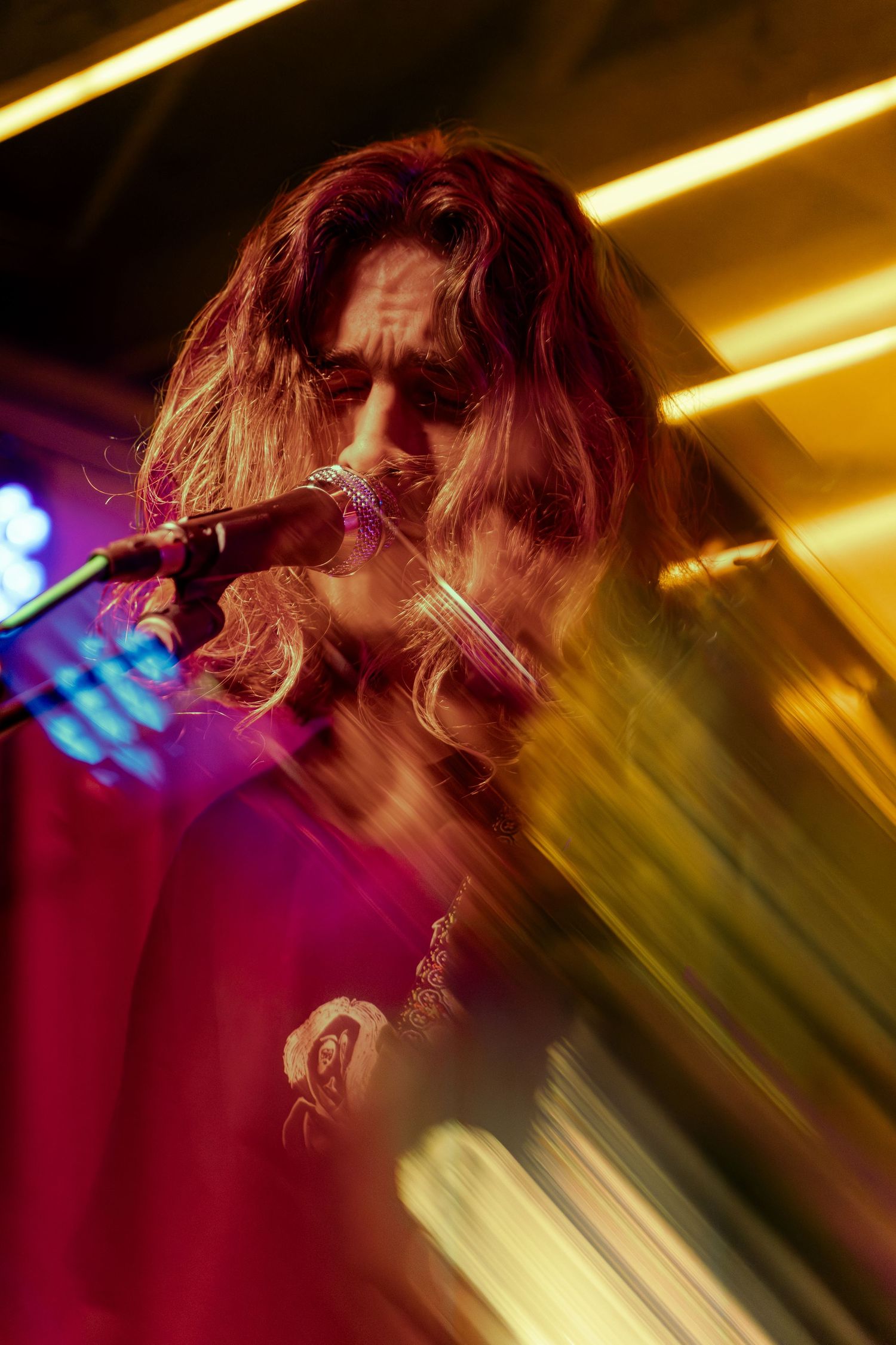 Motion blur captures a dynamic performance moment with golden stage lights and red accents creating an energetic atmosphere.
