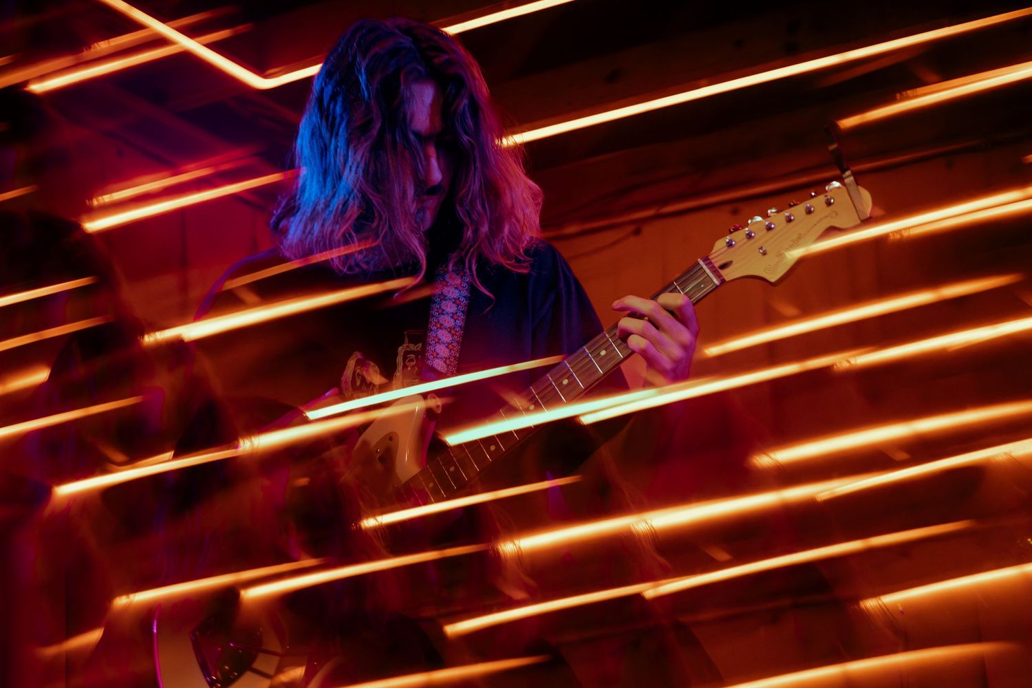 Red neon lights create dramatic diagonal lines across dark ceiling with contrasting blue lighting accent in background.