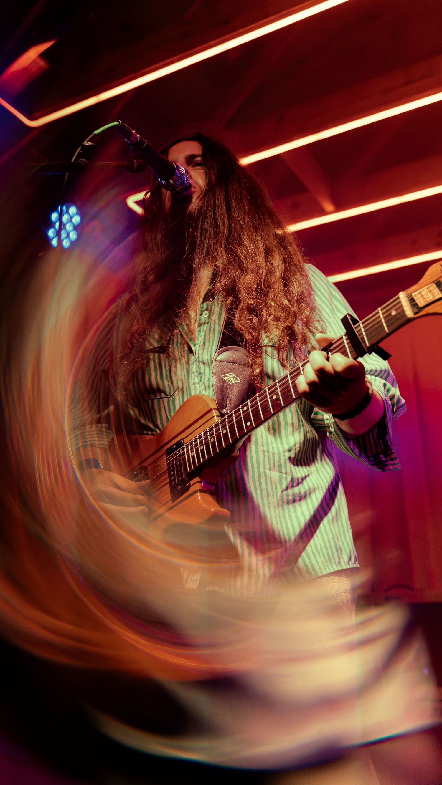 A dynamic motion-blurred series of images showing a musician playing electric guitar under dramatic red stage lighting.
