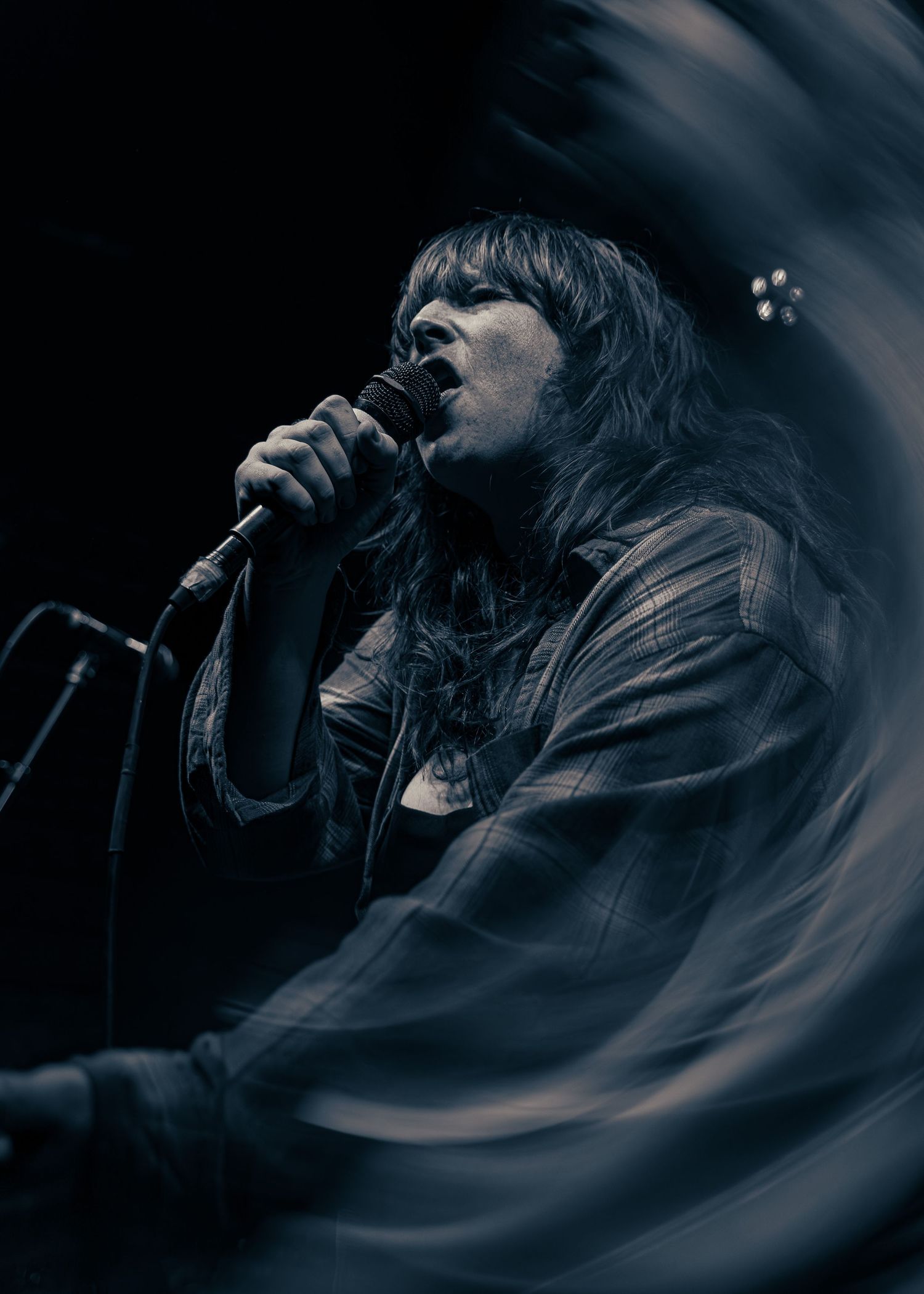 Artistic moody performance photo sequence shows singer silhouetted against dark background with dramatic motion blur effect.