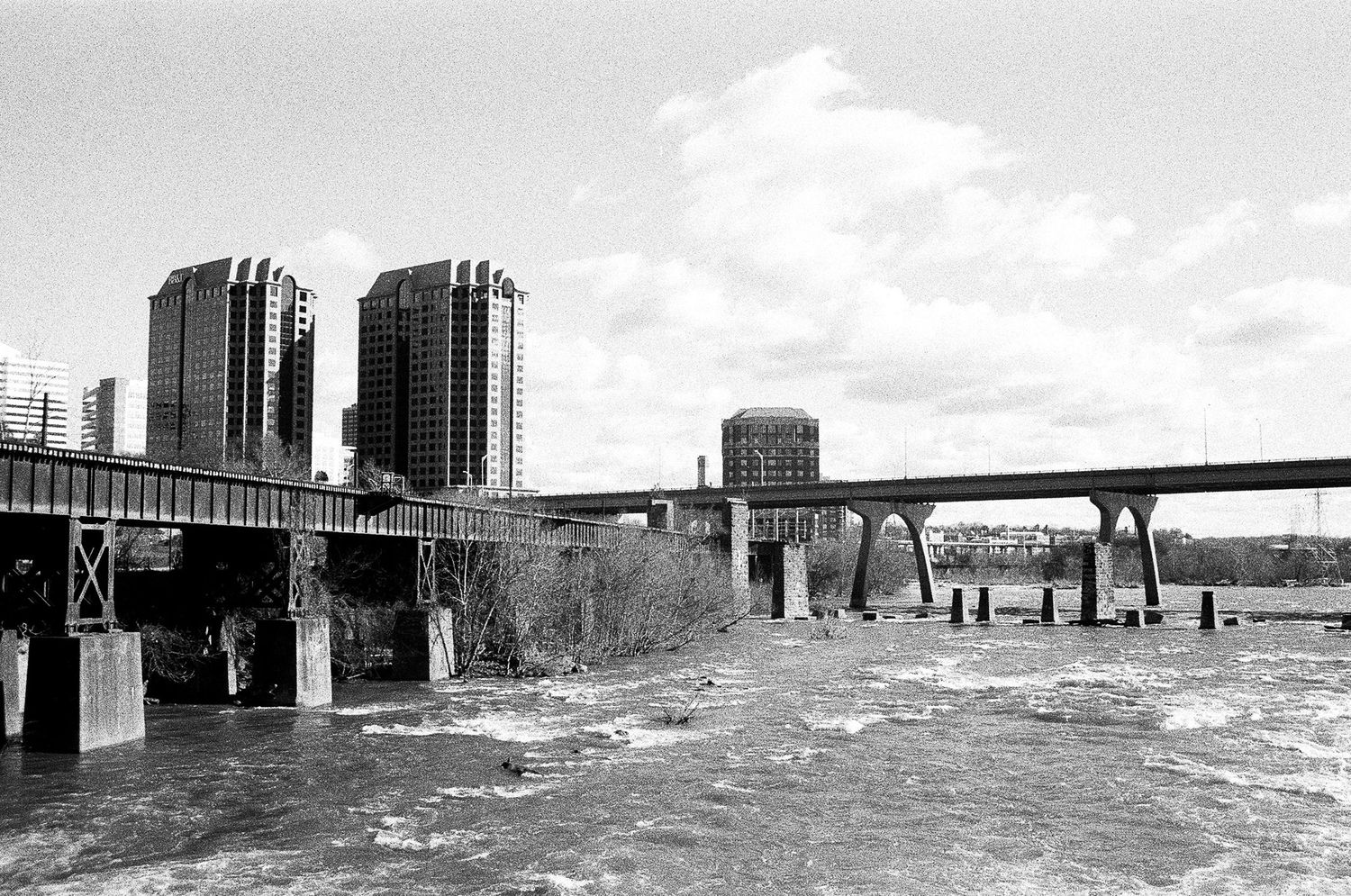 Black and white cityscape showing industrial buildings near a waterfront.