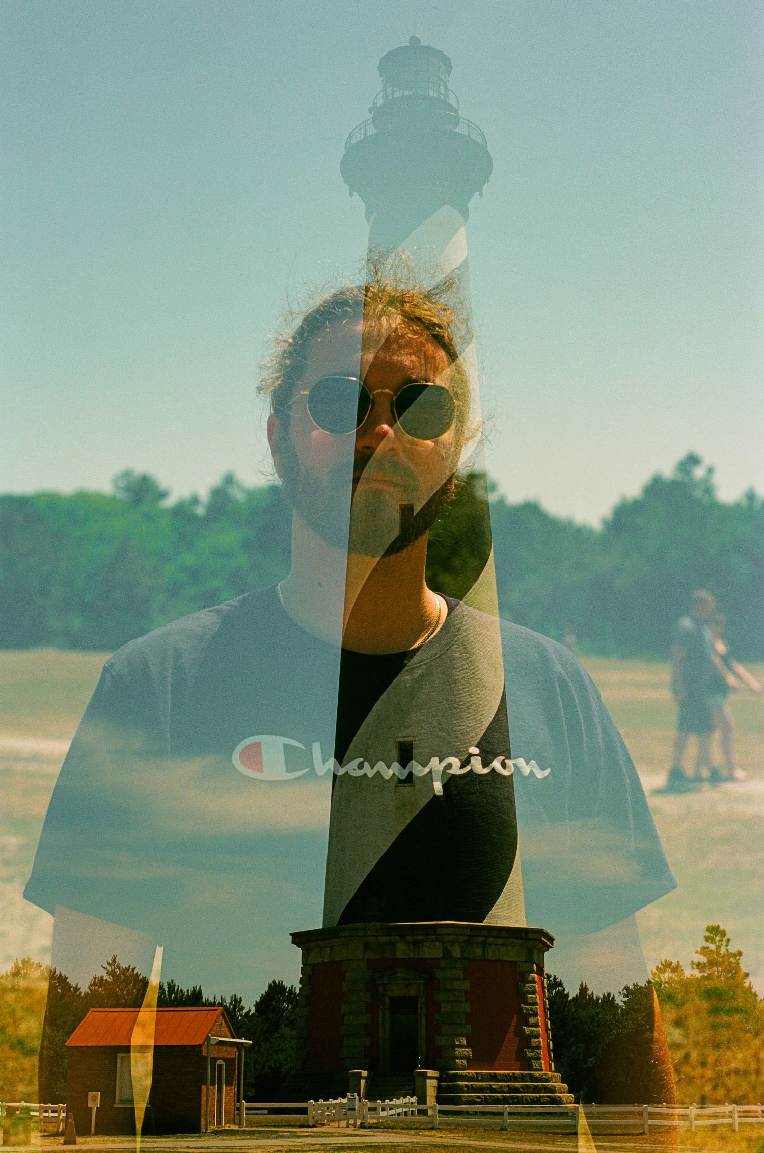 Double exposure photograph combining a lighthouse silhouette with a portrait against a blue sky.