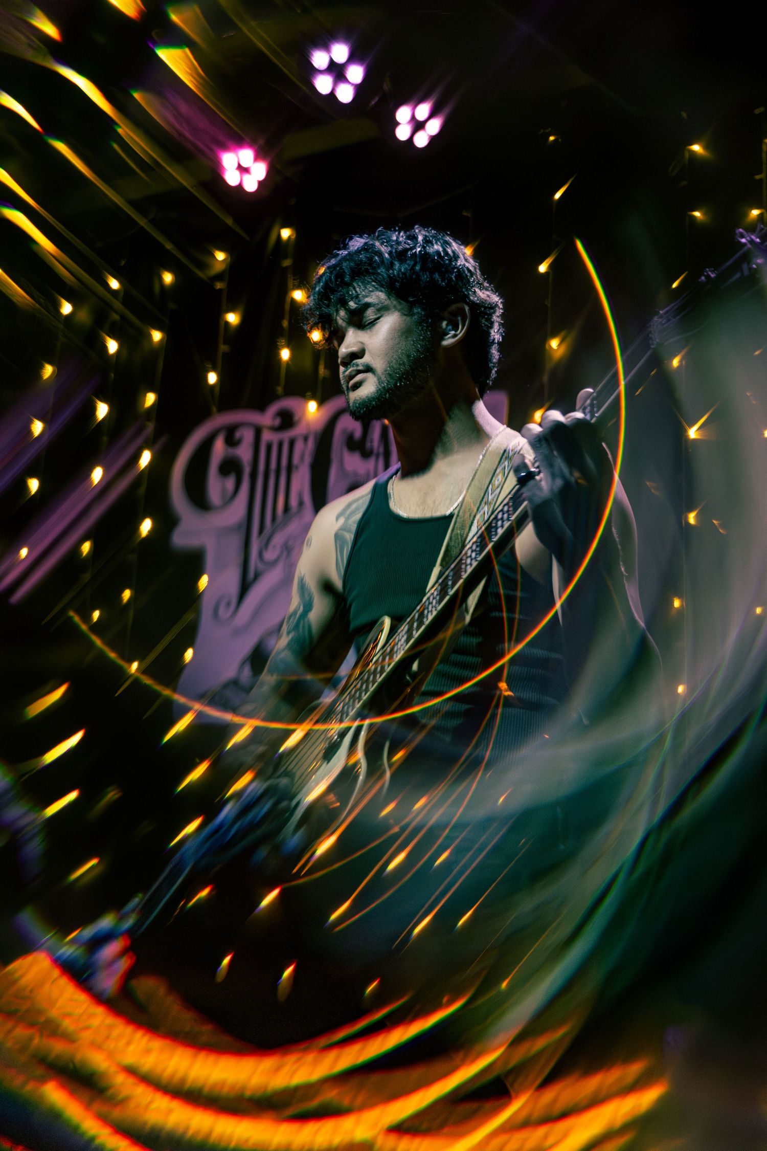 Concert performer illuminated by dynamic yellow and purple stage lighting effects during an energetic performance.