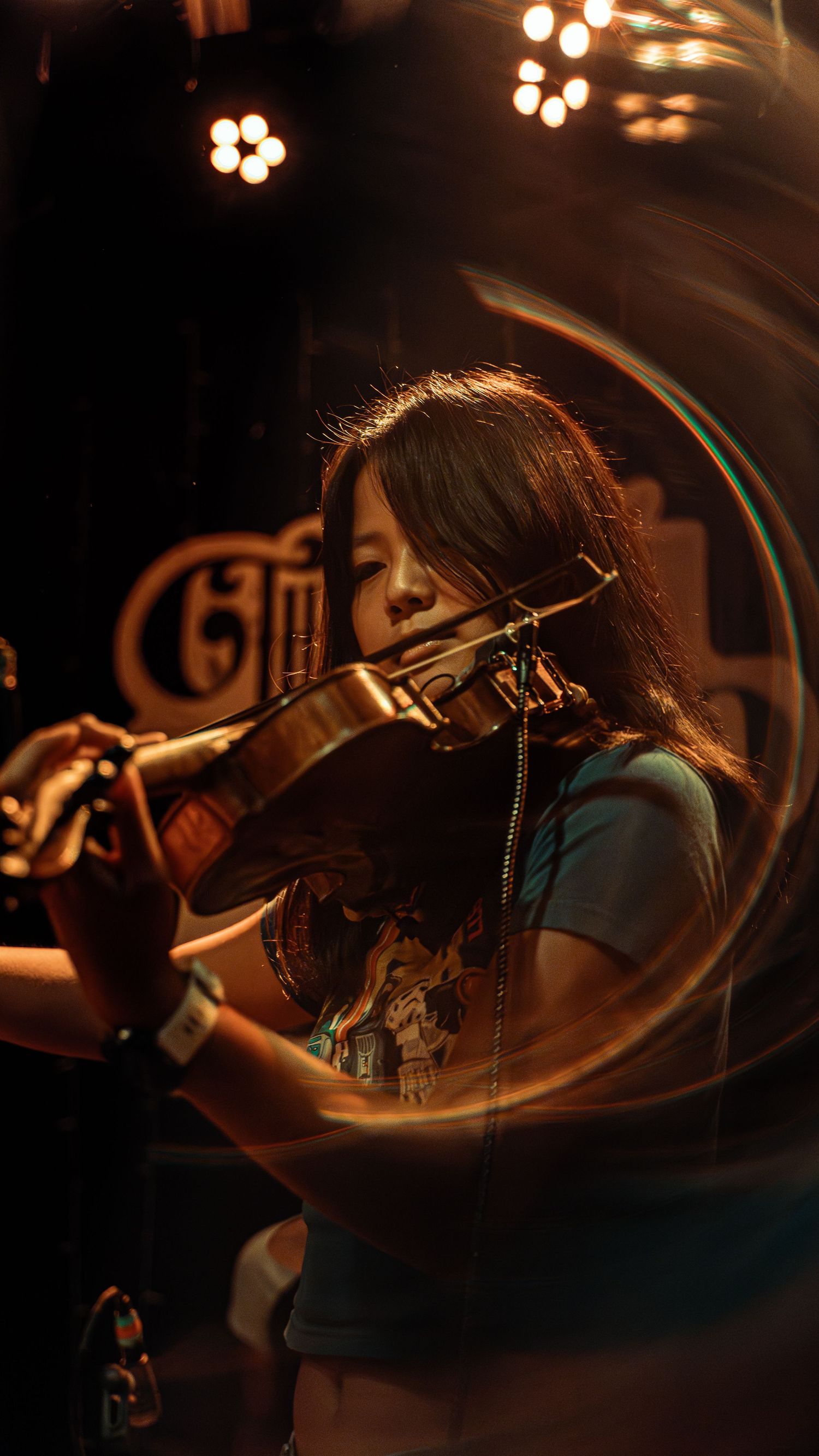 Series of blurred concert photos showing a performer playing violin on stage under warm lighting.
