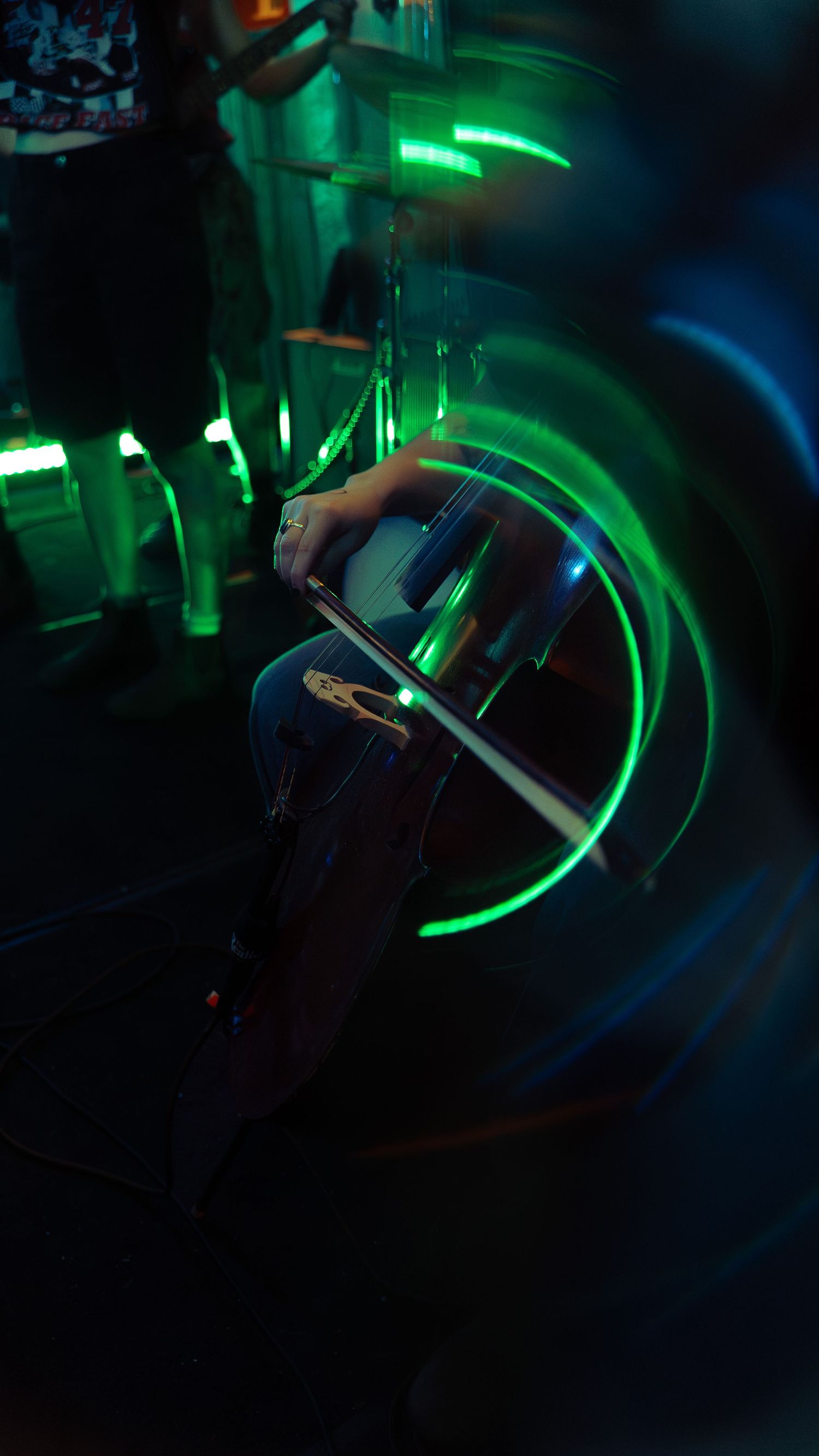 Glowing green and blue neon lights create swirling patterns in a dark nightclub atmosphere.