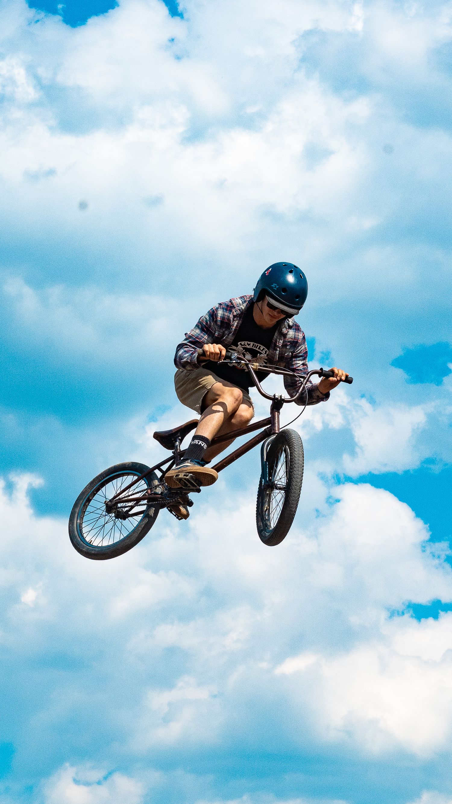 Skilled BMX rider soars through the air performing a high jump trick.