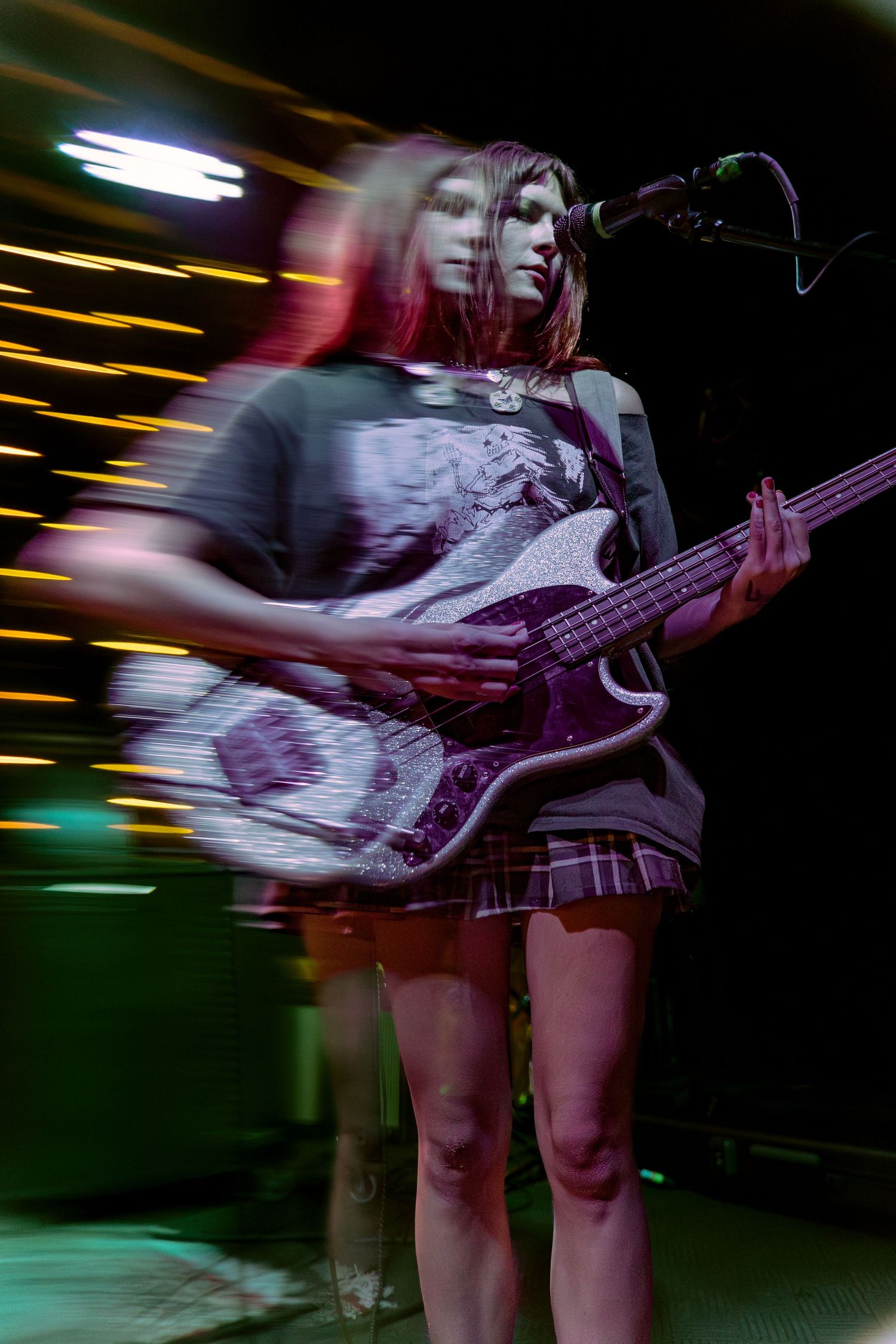 Motion-blurred sequence of a bassist performing on stage with colorful lighting effects creating dynamic movement trails.
