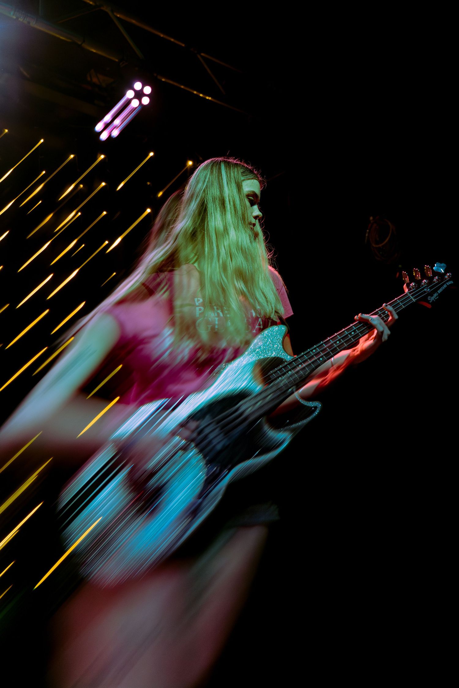 Sequence of motion-blurred photographs showing a guitarist performing on stage with colorful green and blue lighting effects.