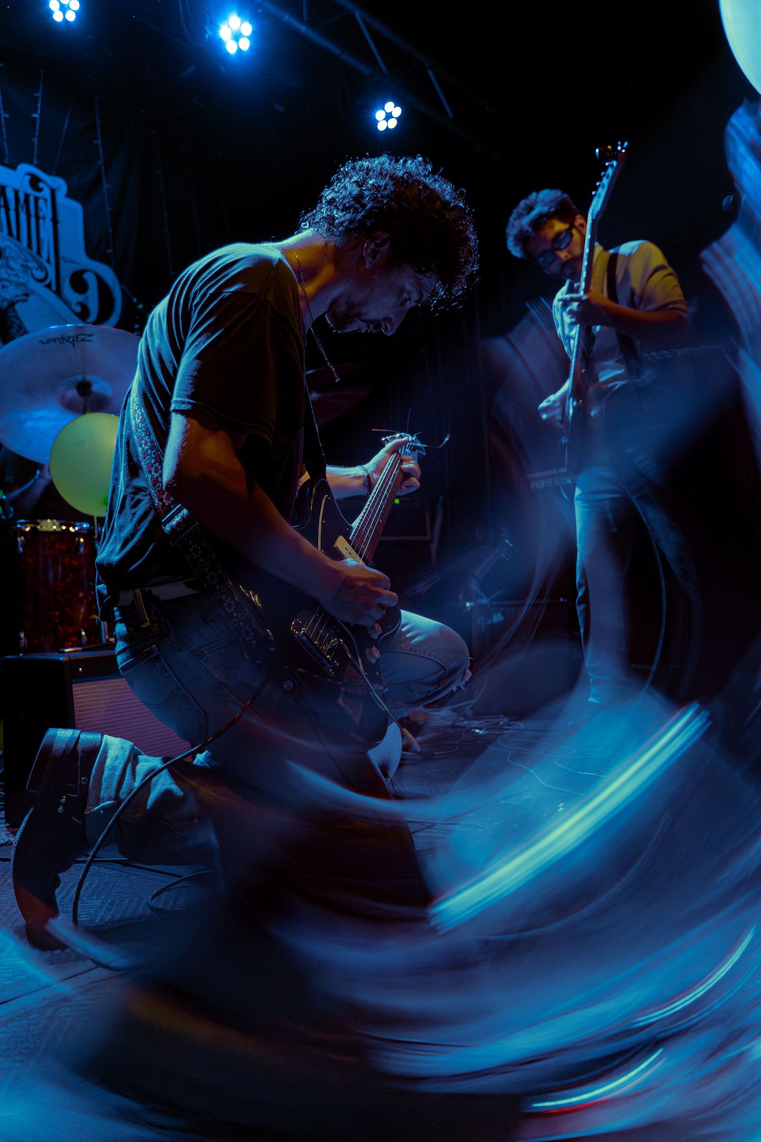 Motion blurred photograph sequence of performers on stage bathed in atmospheric blue lighting during a live show.