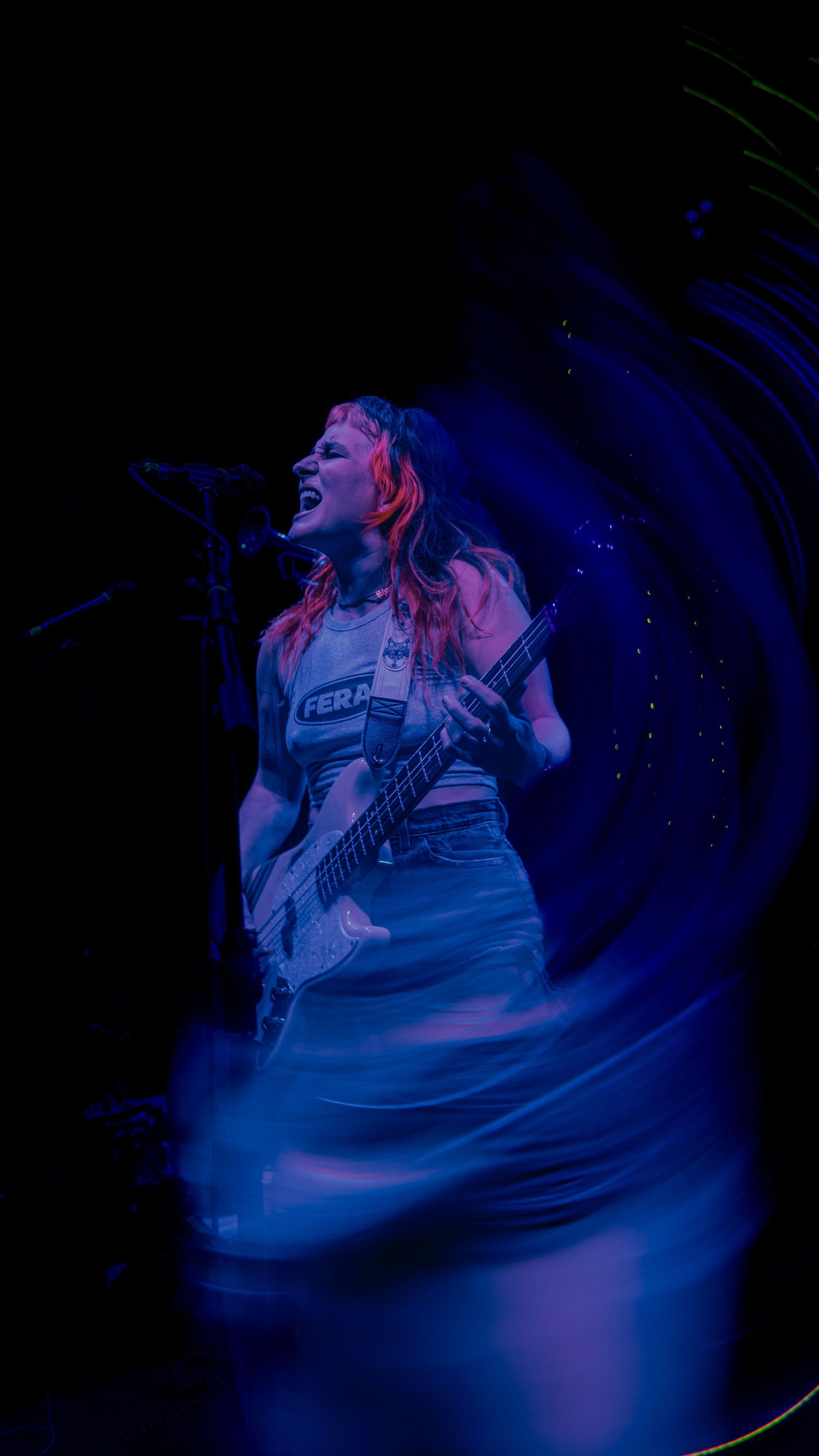 Concert performer with guitar bathed in dramatic blue stage lighting during an energetic performance.