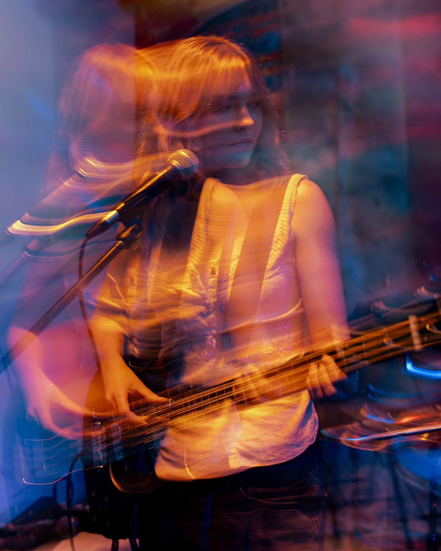 Motion-blurred musical performance with bassist captured in streaks of orange and blue light.