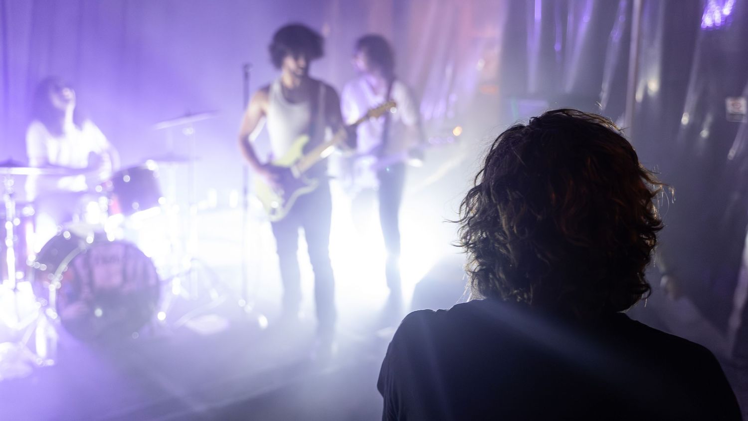 Concert venue illuminated in purple stage lights creating a dramatic atmosphere during performance.