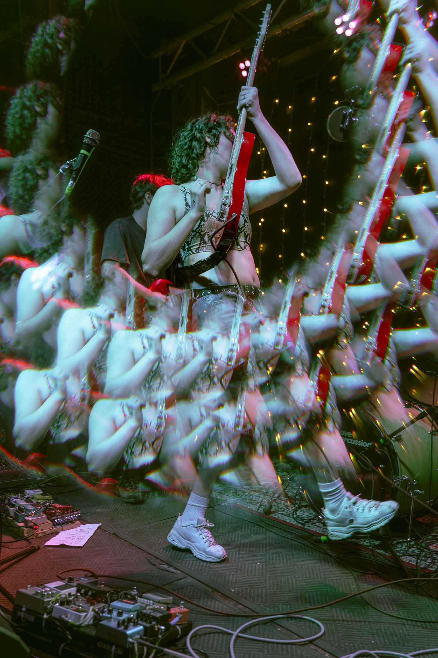 Multiple exposure photo shows motion blur of feet and legs dancing in white sneakers on a dark stage.