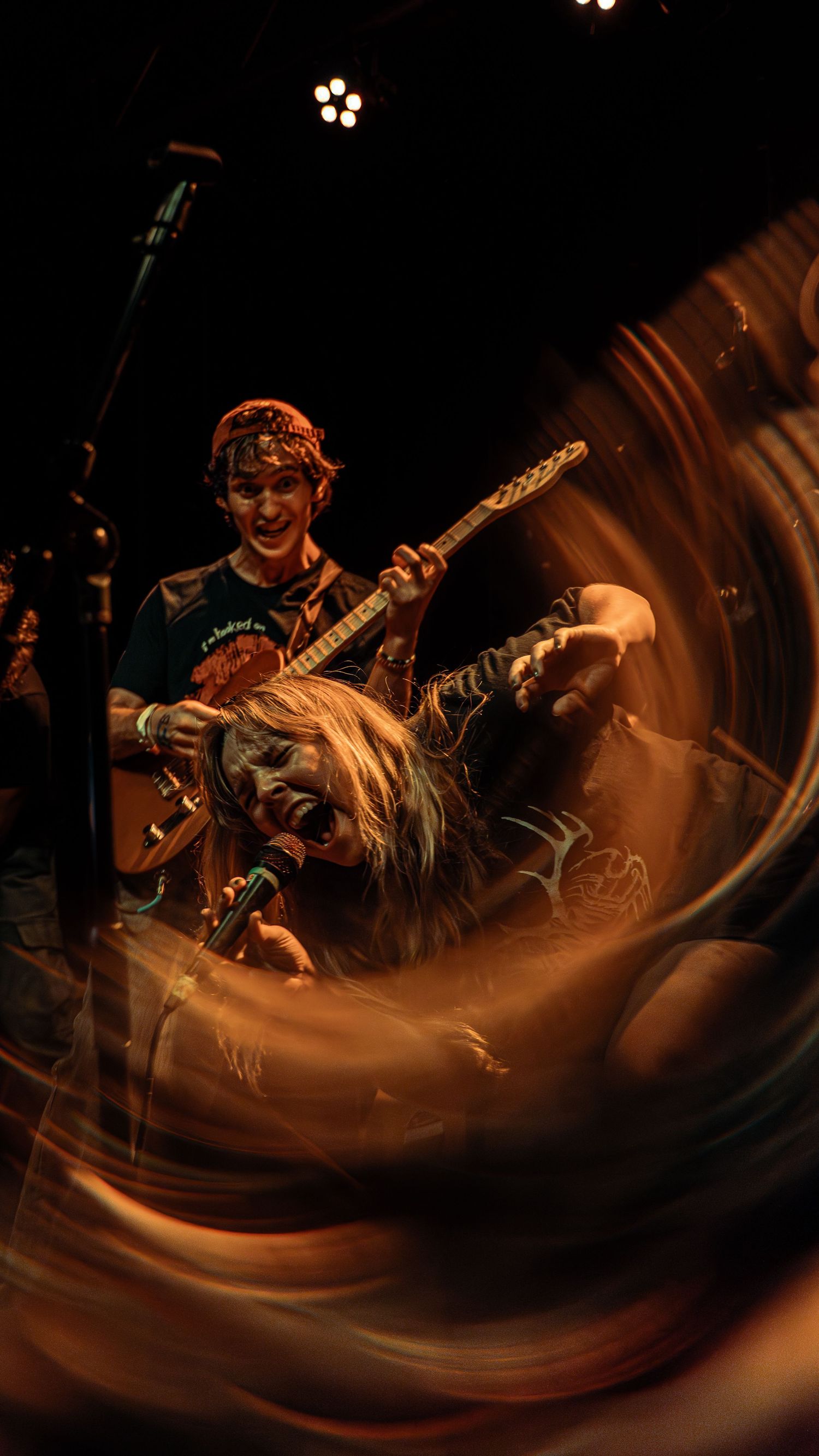 Dynamic concert photograph capturing musicians performing on stage with dramatic motion blur and warm lighting effects.