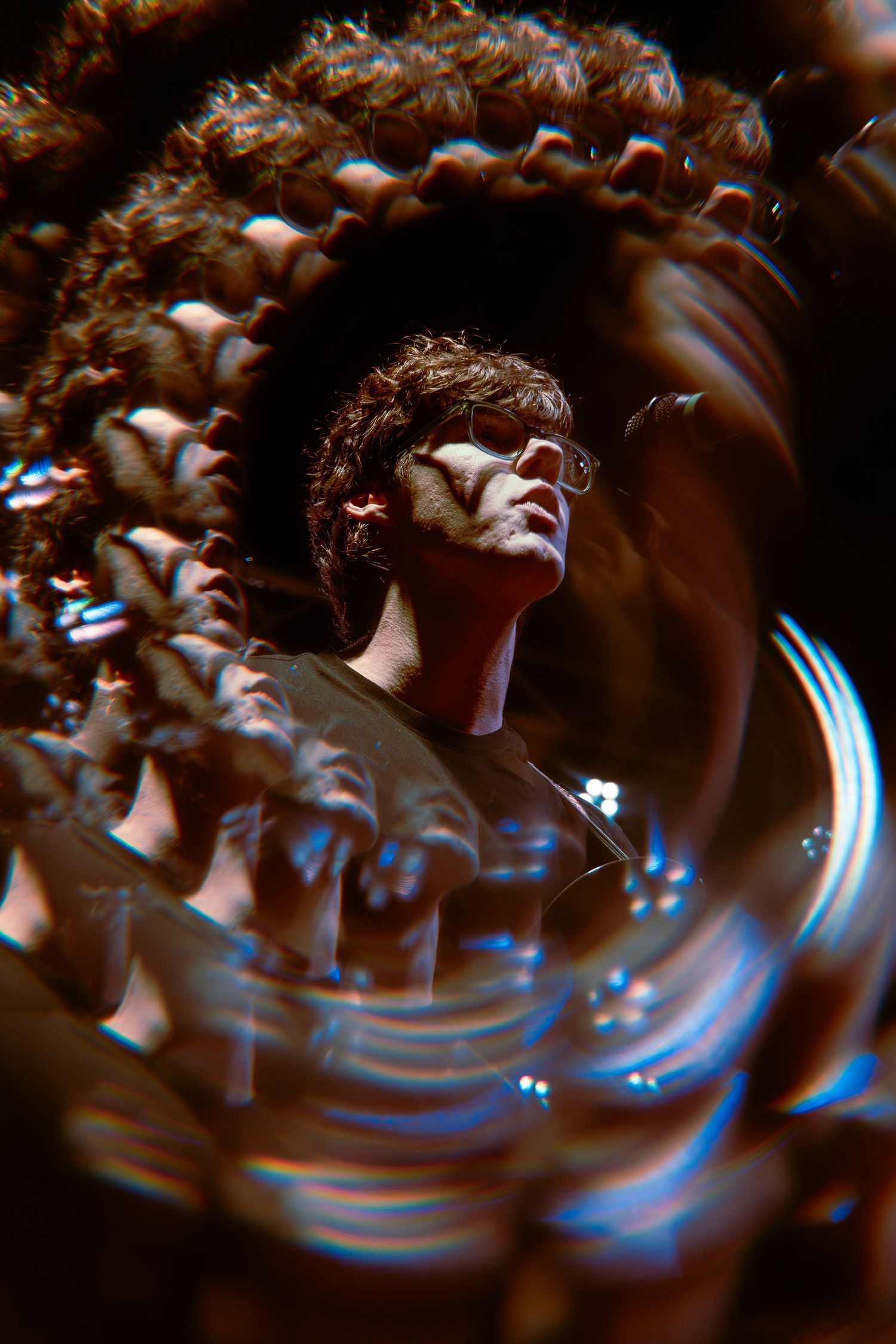 Artistic abstract photograph showing a distorted figure viewed through a spiral effect with glowing blue motion trails.
